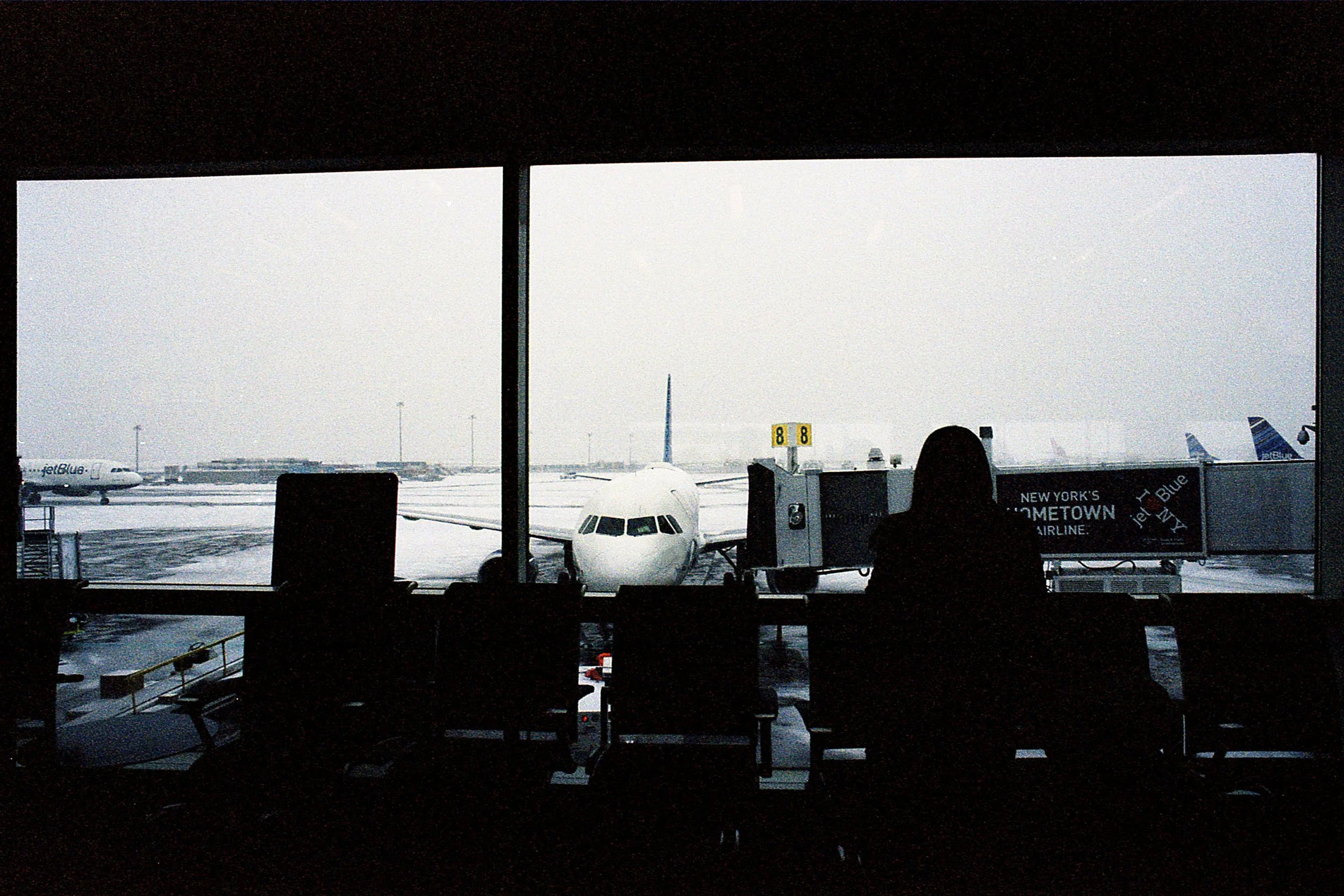 Color photo looking out at an airplane on the tarmac in snow