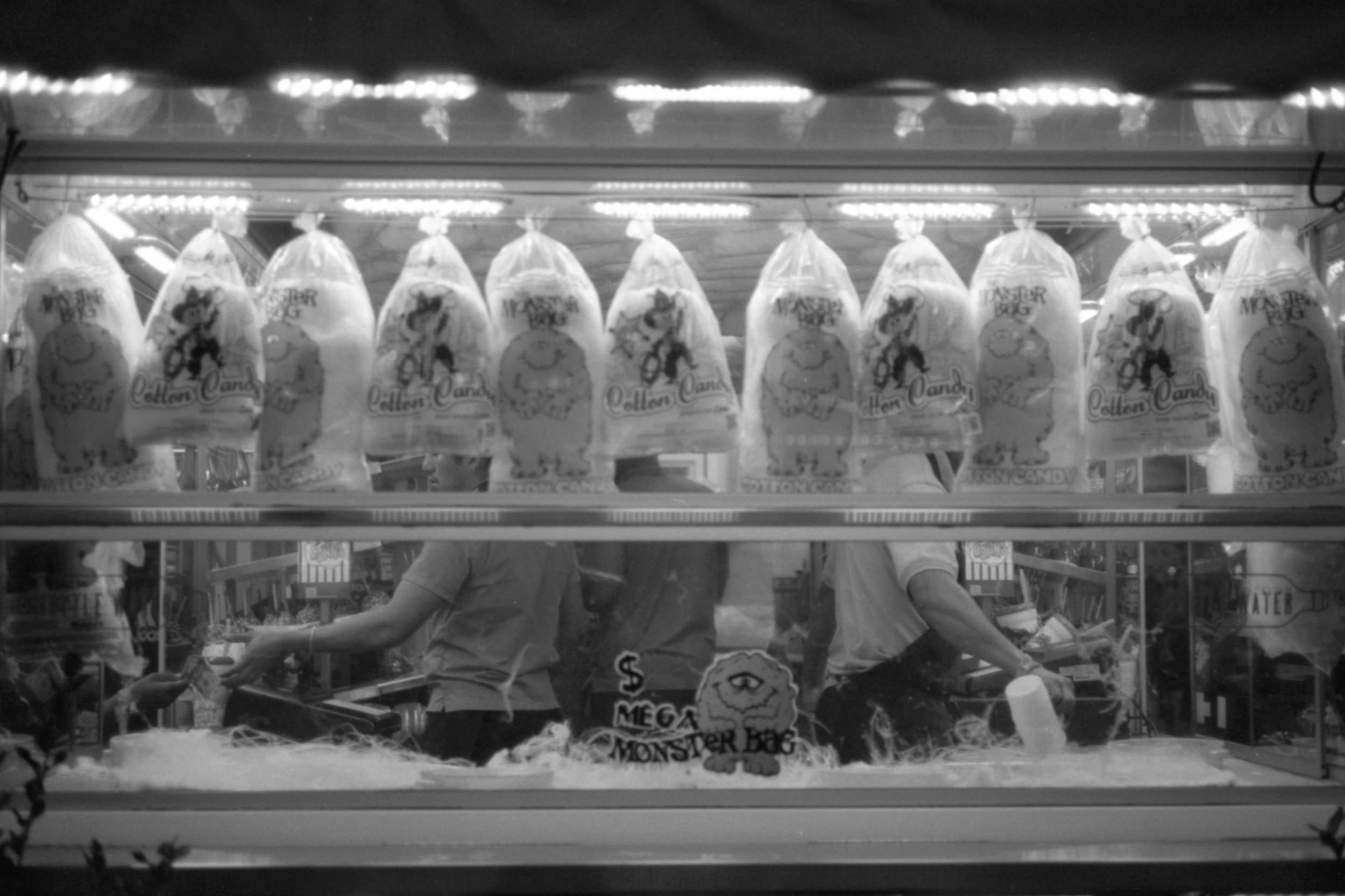 Clothes sold at a stall, featuring plastic bags with cartoon characters and text for Halloween candy, with two people visible behind the counter managing transactions.