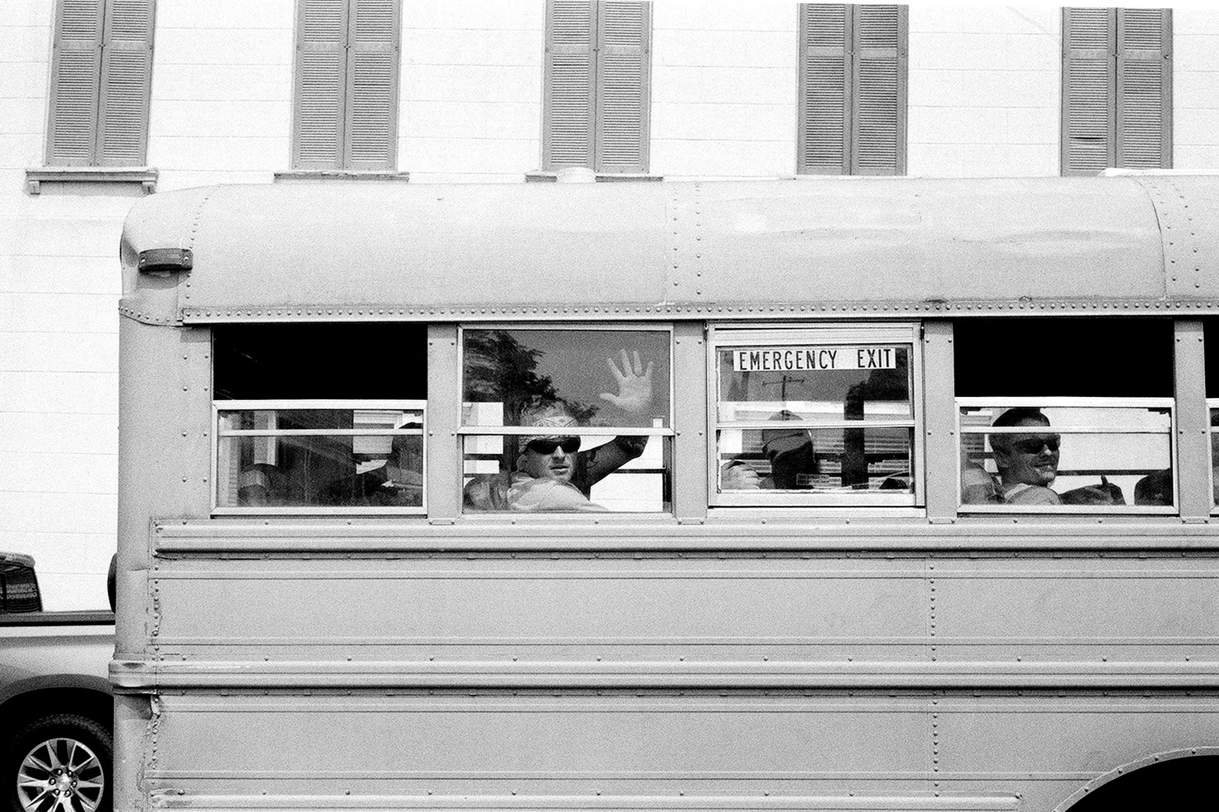 Man in prison bus waving into camera