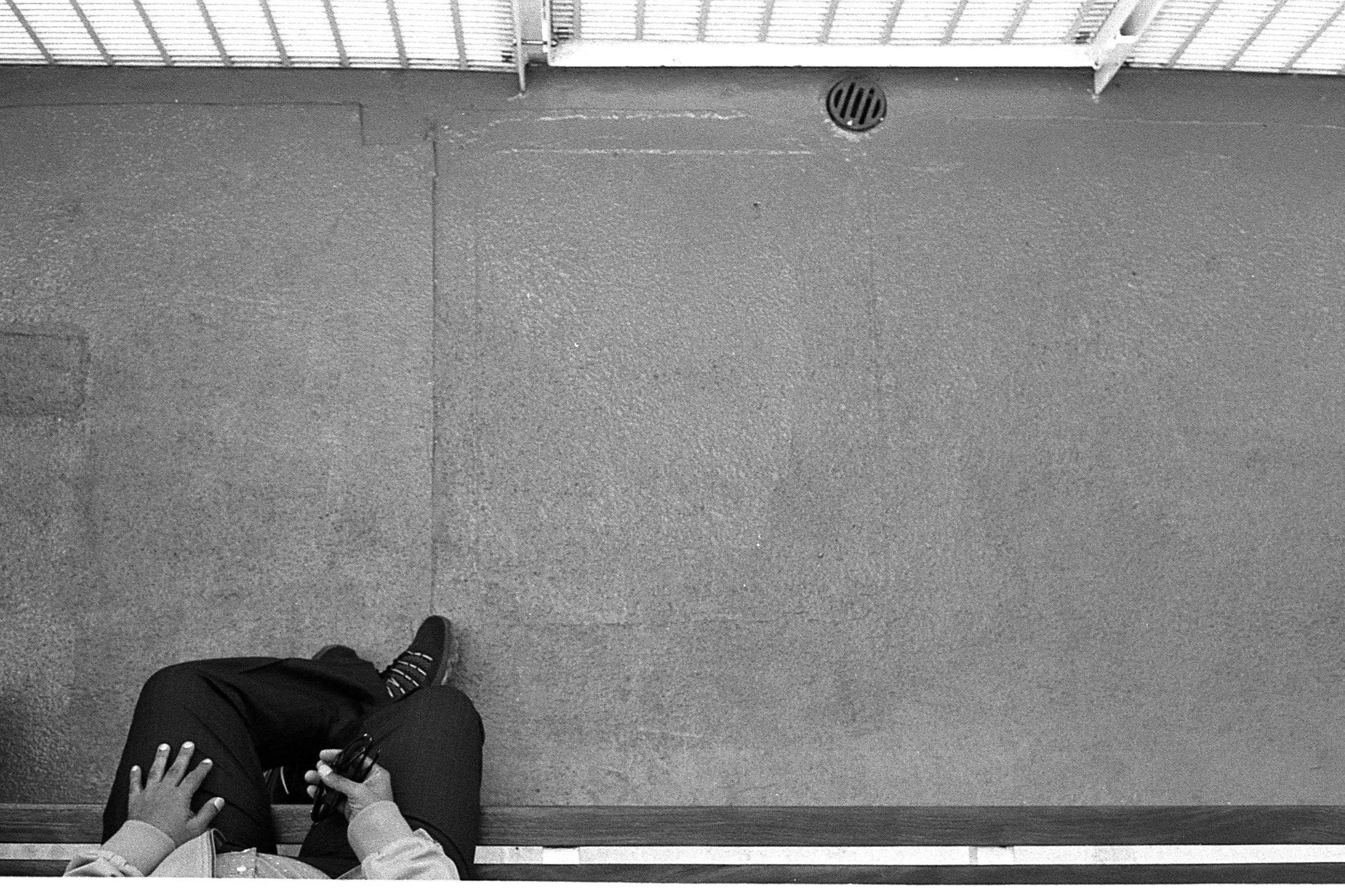 Black and white photo looking down from above at the hands of a man on his lap