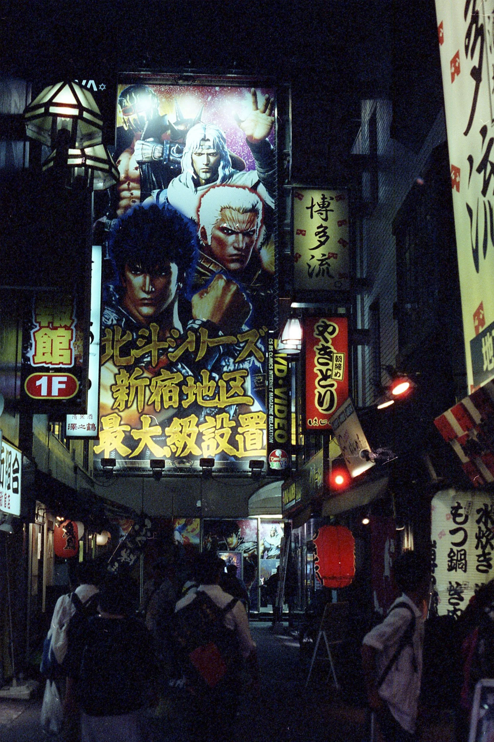 Night scene of a busy urban street filled with illuminated signs and billboards in Japanese, crowd of people walking, some wearing backpacks and carrying shopping bags.