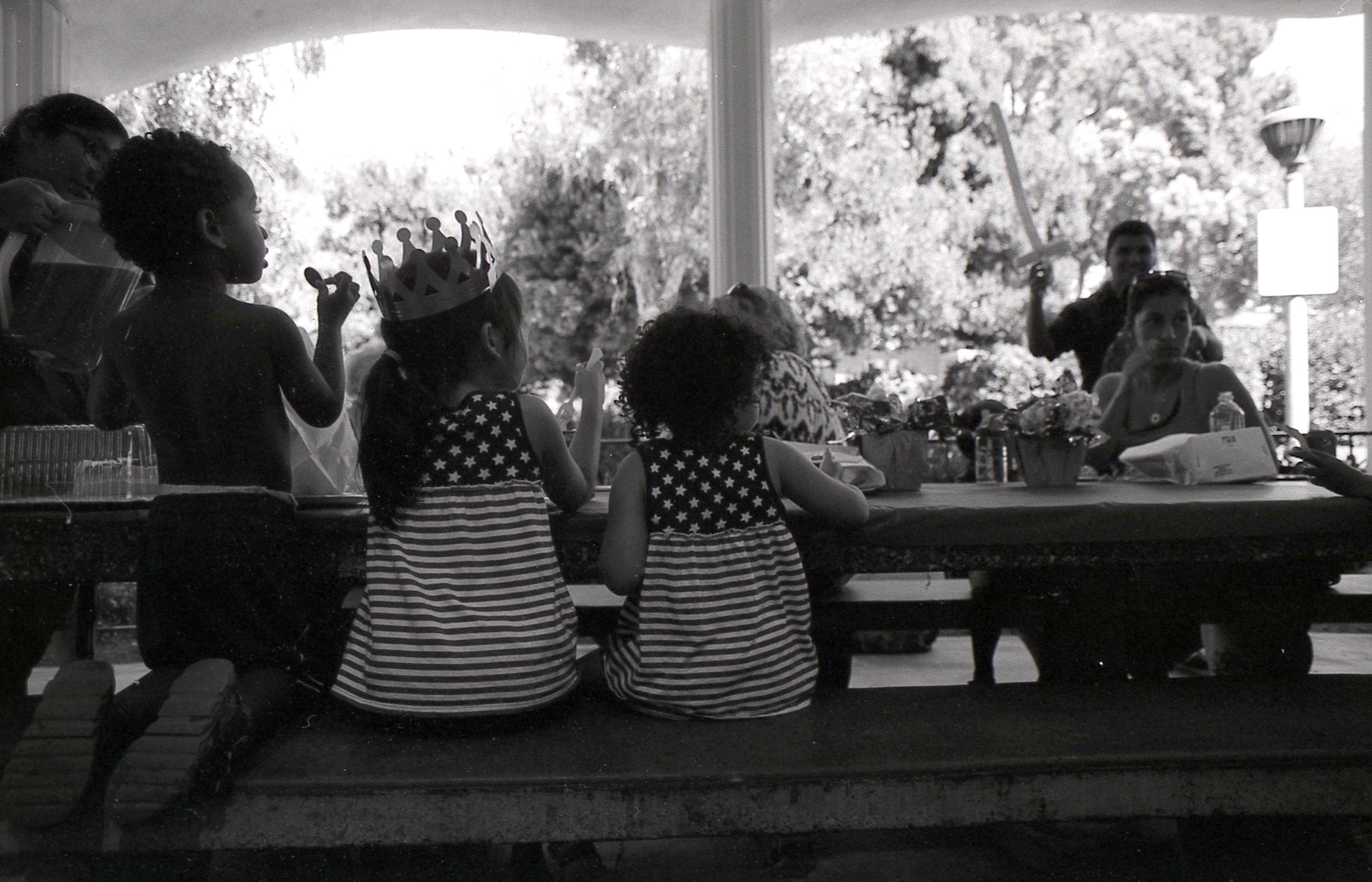 Black and white photo of a children's birthday party, focused on two girls in American Flag dresses