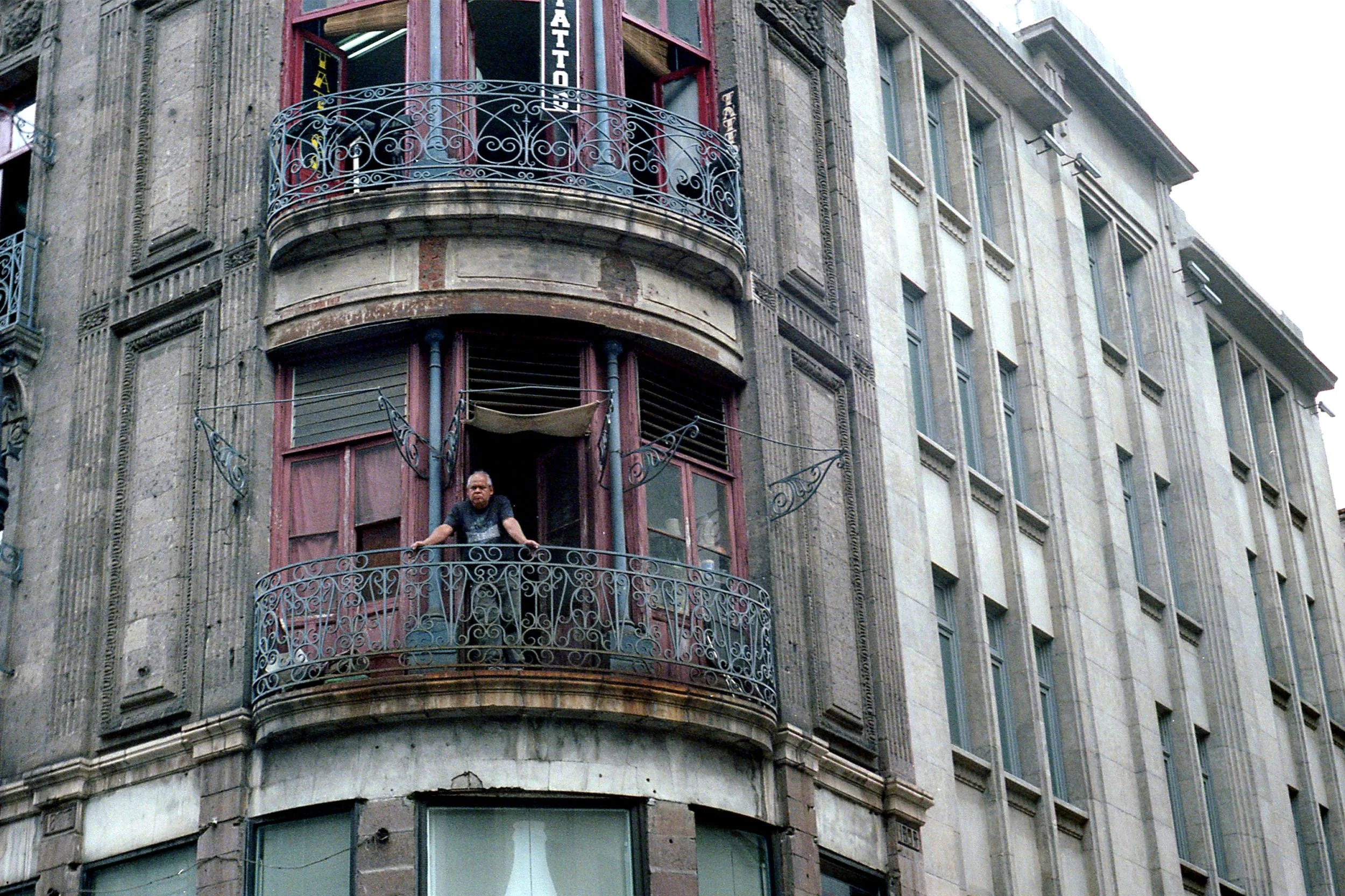 Color photo of man looking down from balcony