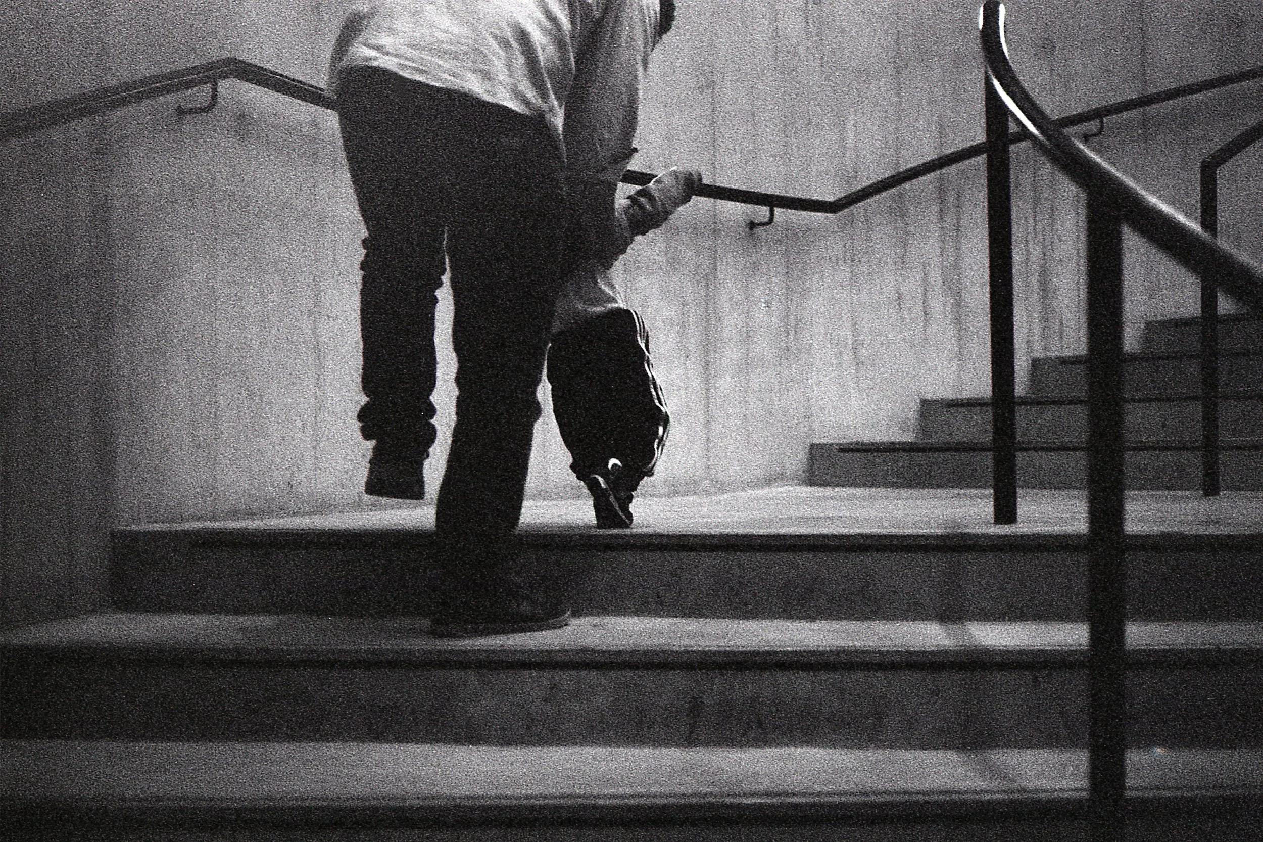 black and white photo of a man helping a toddler up stairs