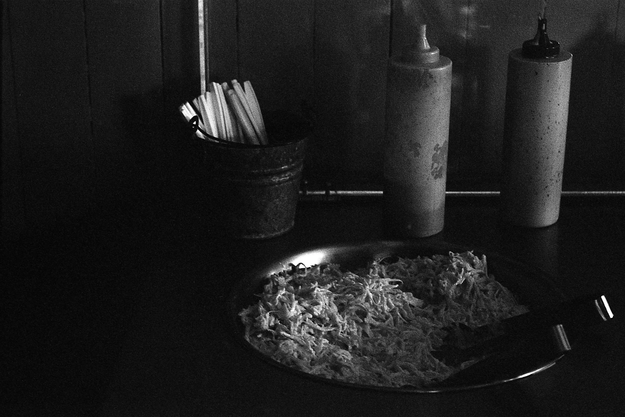 Black and white photo of a bowl of lettuce and condiments
