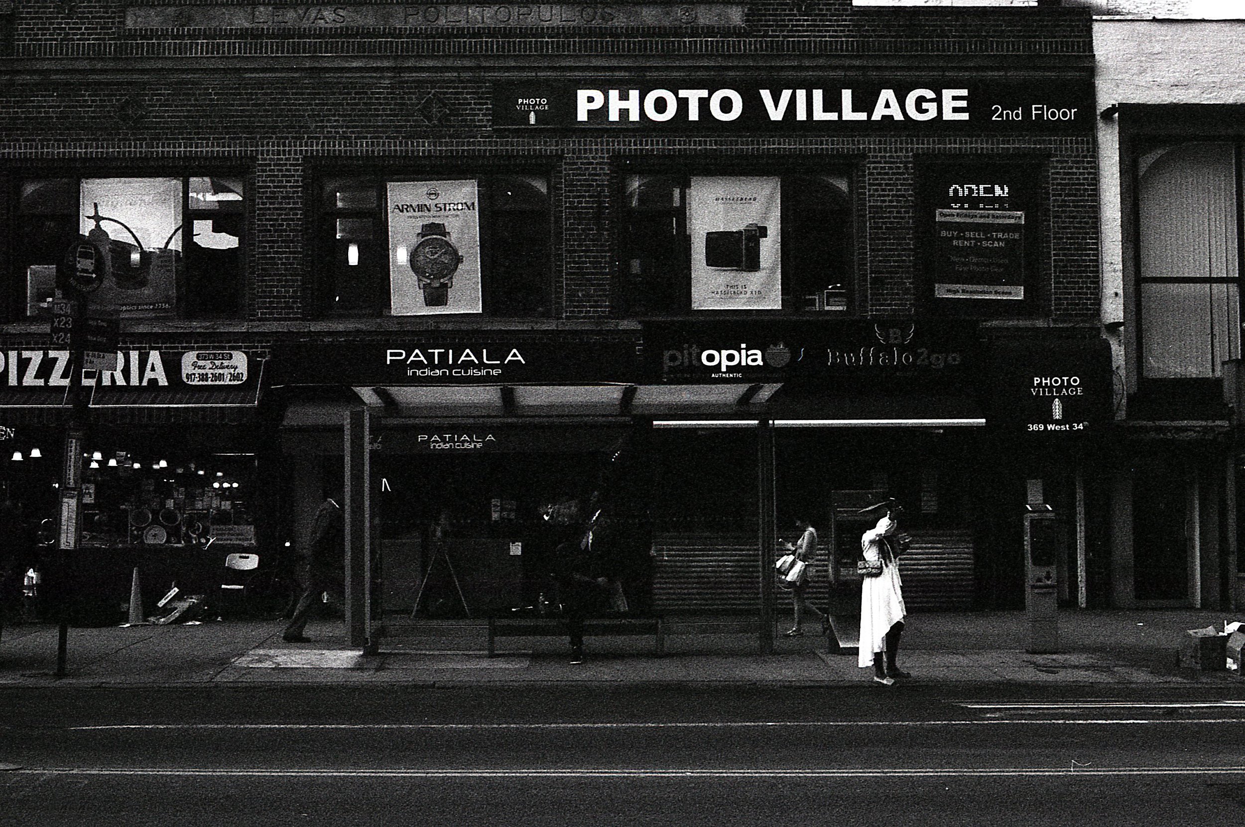 Black and white photo of a woman hailing a taxi in a graduation outfit