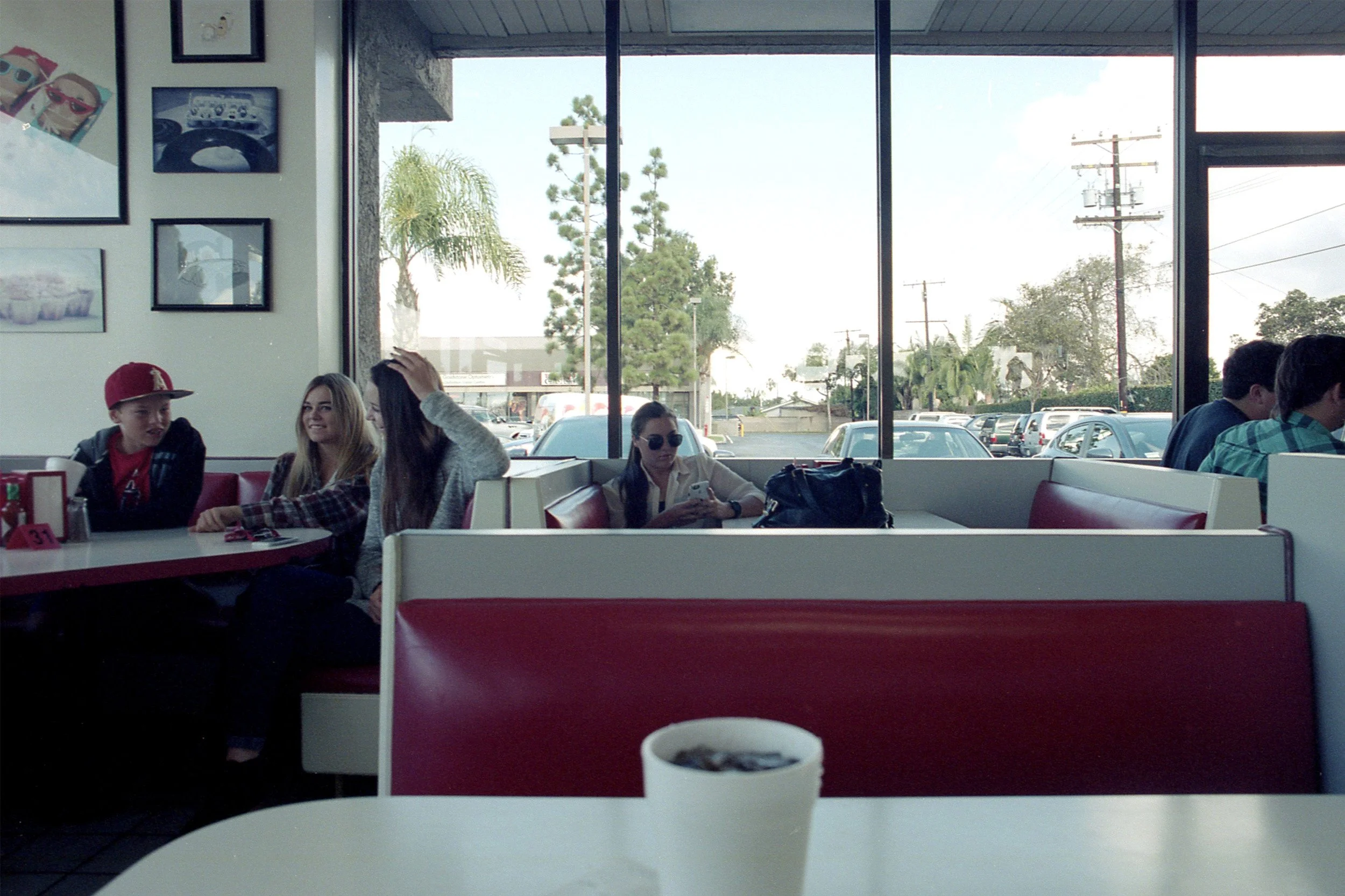 Color photo focused on a girl on her phone in a diner booth