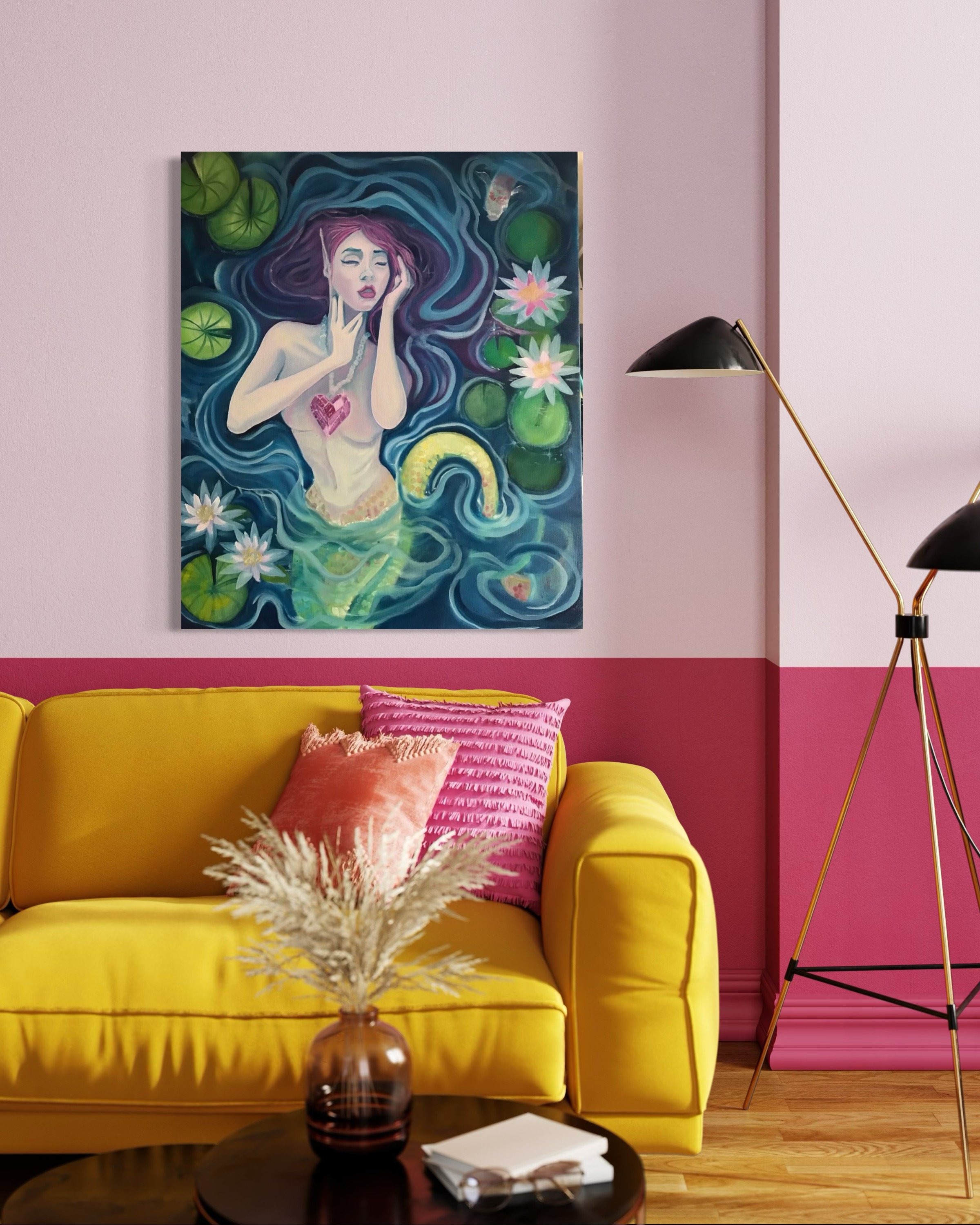 A colorful painting of a mermaid with purple hair, lying in a pond surrounded by lily pads and pink water lilies, with a pink wall behind the artwork. A yellow sofa with pink pillows is in the foreground, and a black floor lamp with gold accents stan