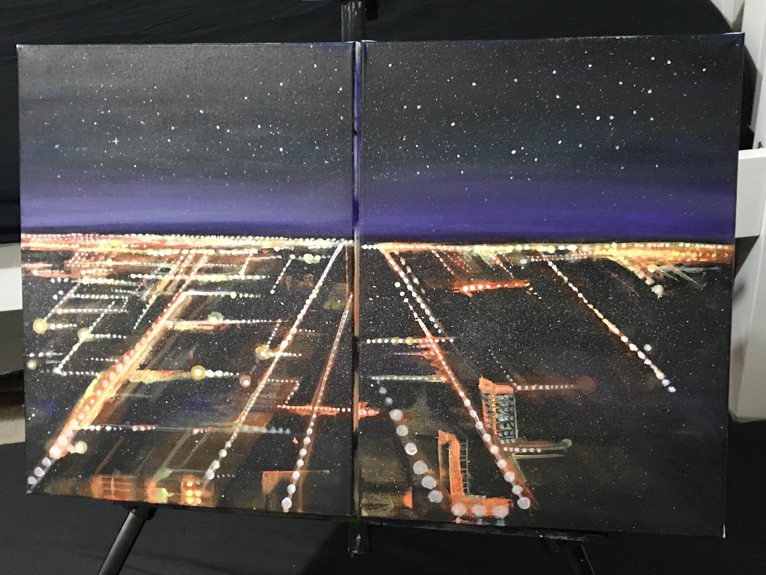 Nighttime aerial view of a city with illuminated streets and a starry sky.
