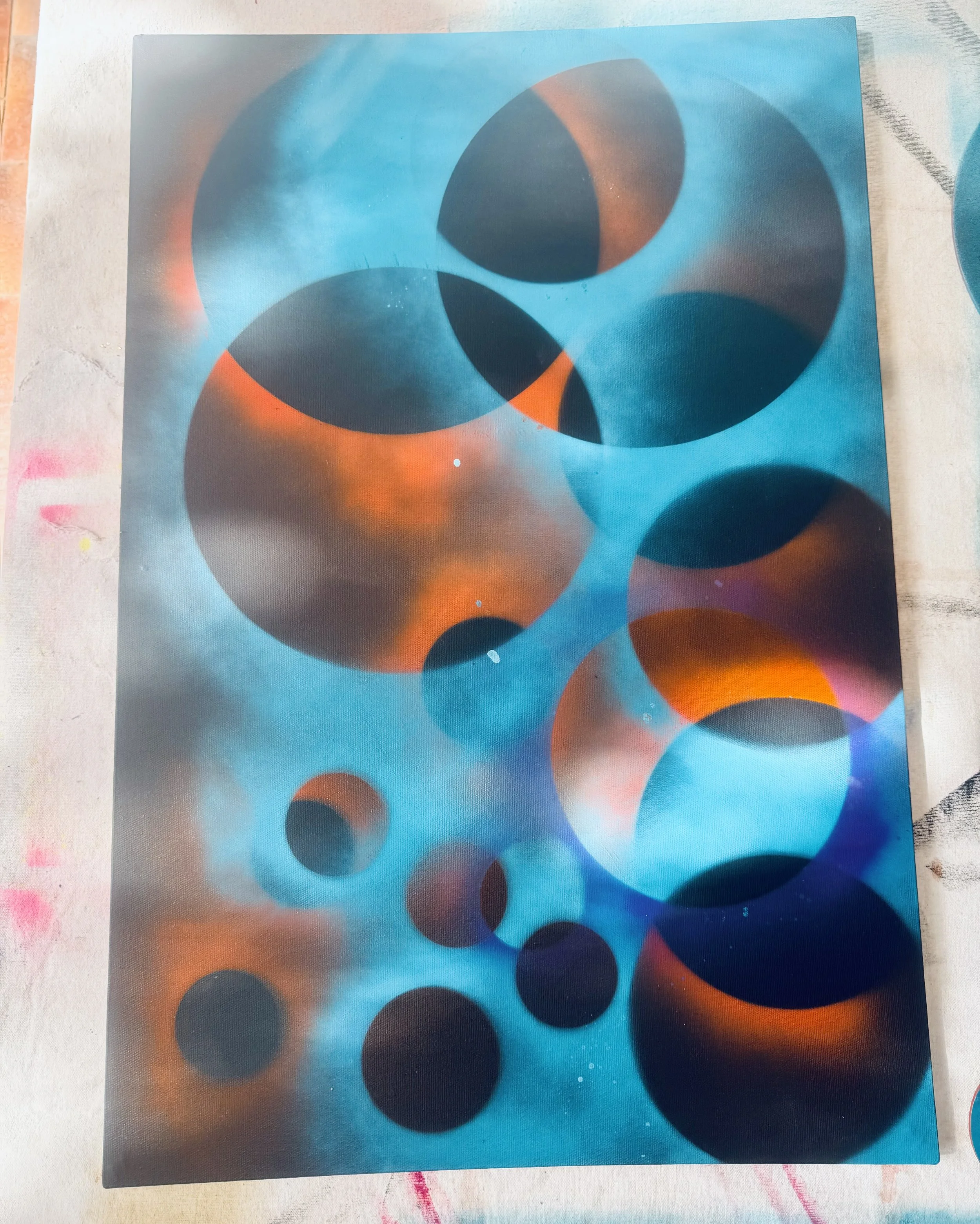 Abstract painting featuring numerous overlapping circles in shades of blue, orange, and black with a cosmic or nebula-like background.