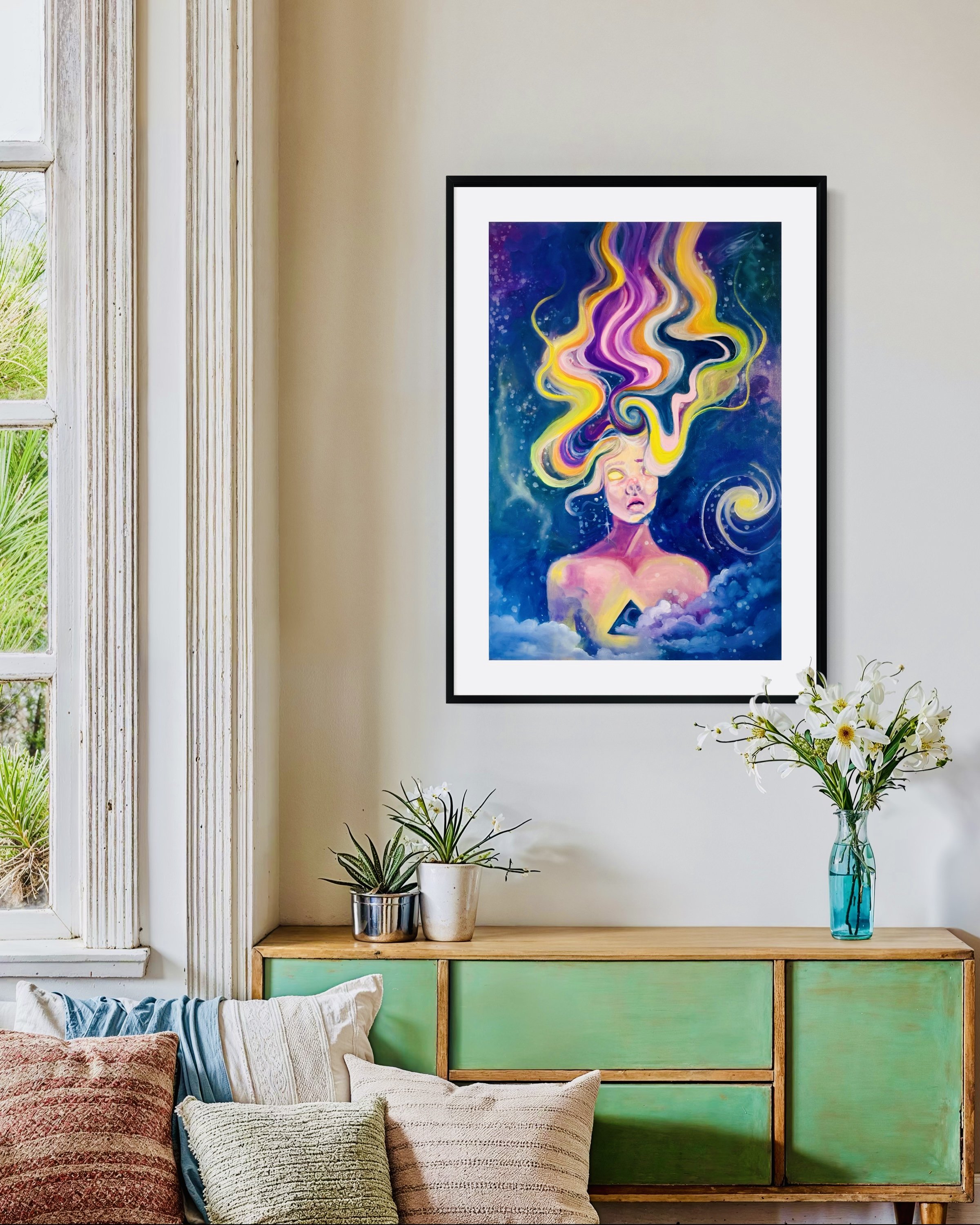 A colorful abstract painting of a woman with swirling yellow, pink, and purple hair hanging on a wall in a living room. The room has a green wooden sideboard, a window with white trim, and vases with flowers and plants.