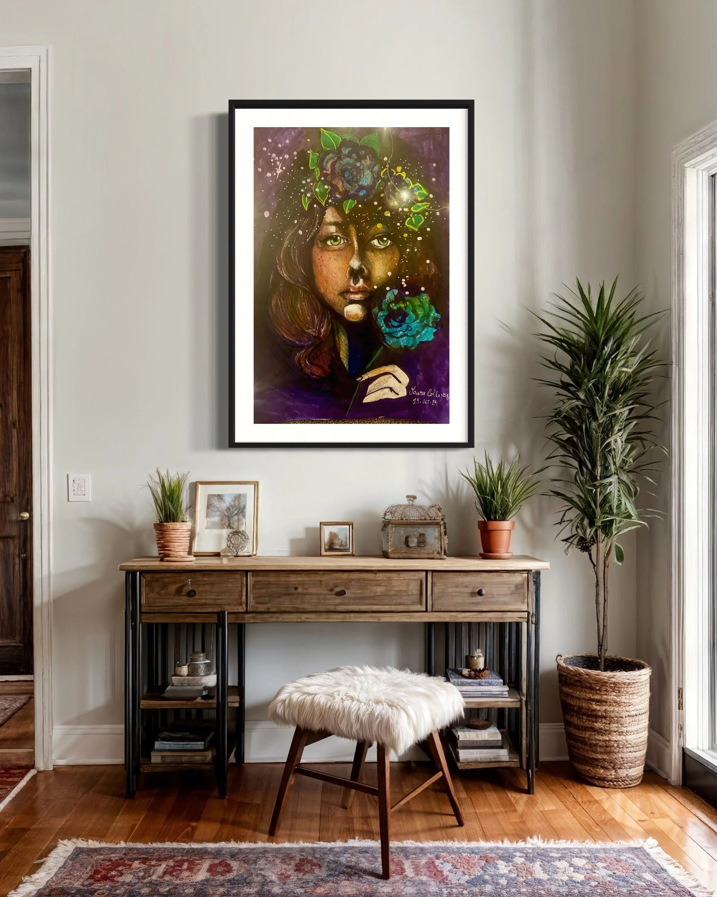 A decorated living room wall featuring a large framed colorful portrait of a woman with floral elements on her head. Below the portrait is a wooden console table with plants, picture frames, and decorative items. In front of the table is a stool with
