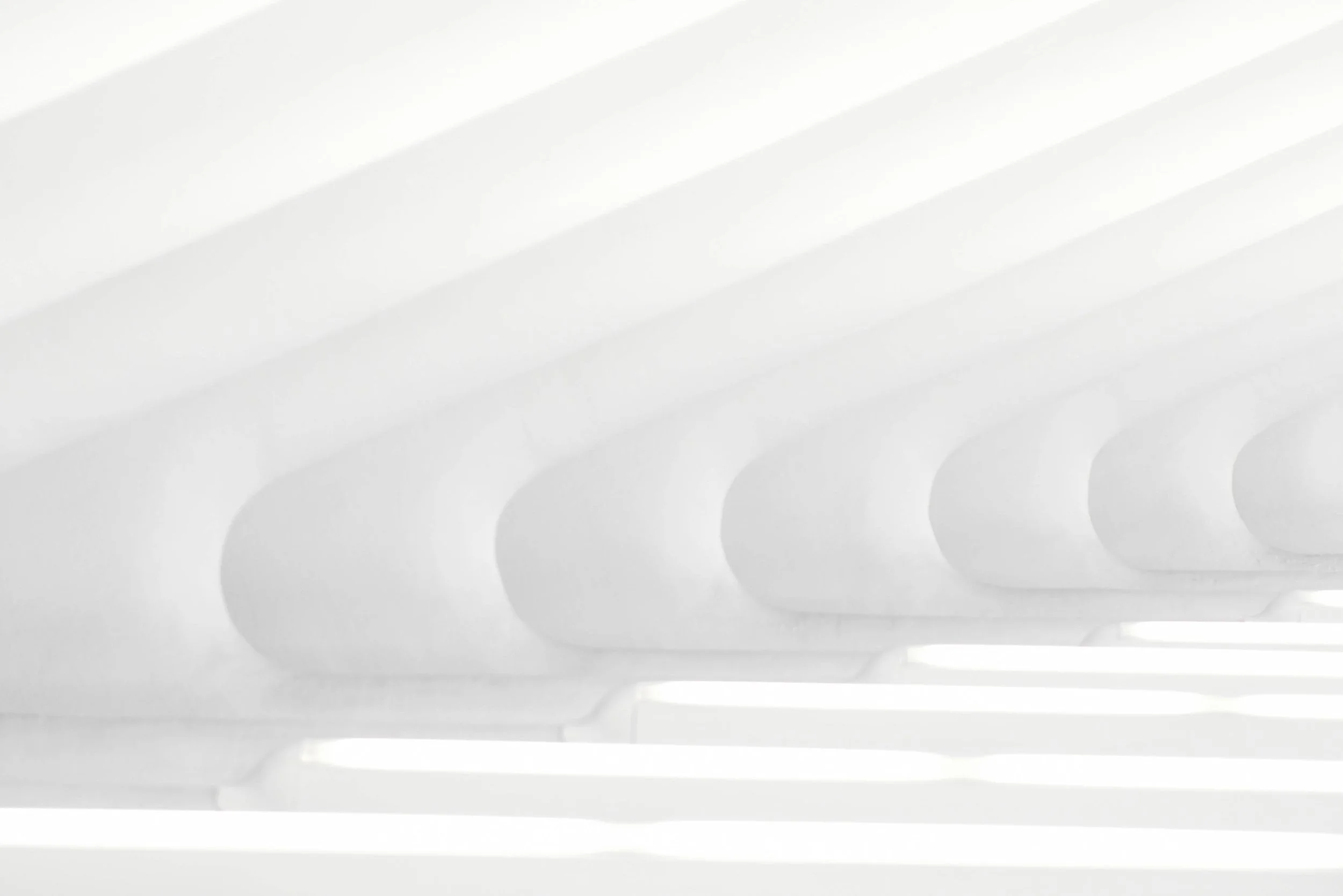 Close-up of white horizontal slats with shadows, likely part of a modern vent or architectural feature.