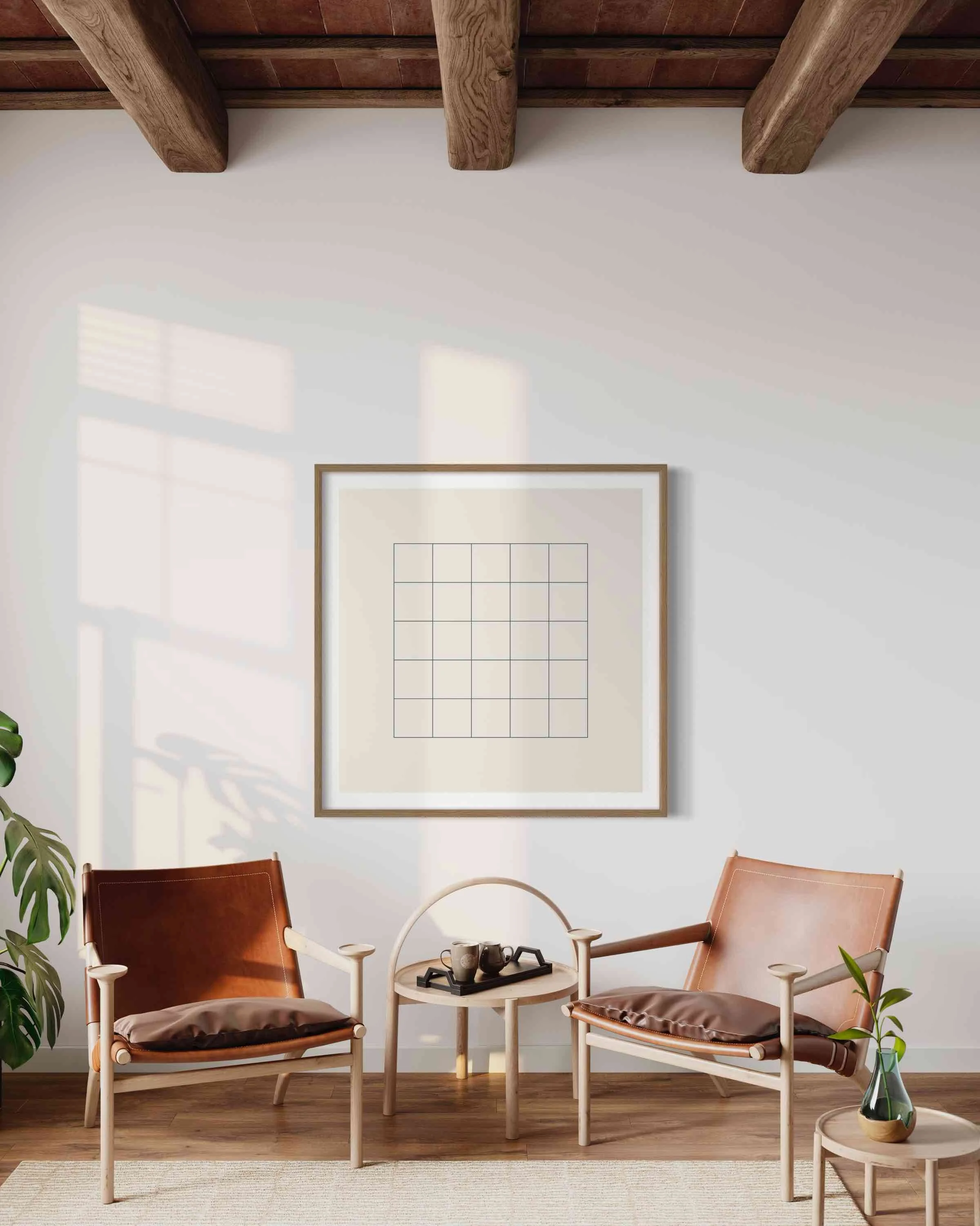 Living room with two leather chairs and a small side table with black cups, a green plant in a glass vase, a framed art piece on the wall, and wooden ceiling beams.