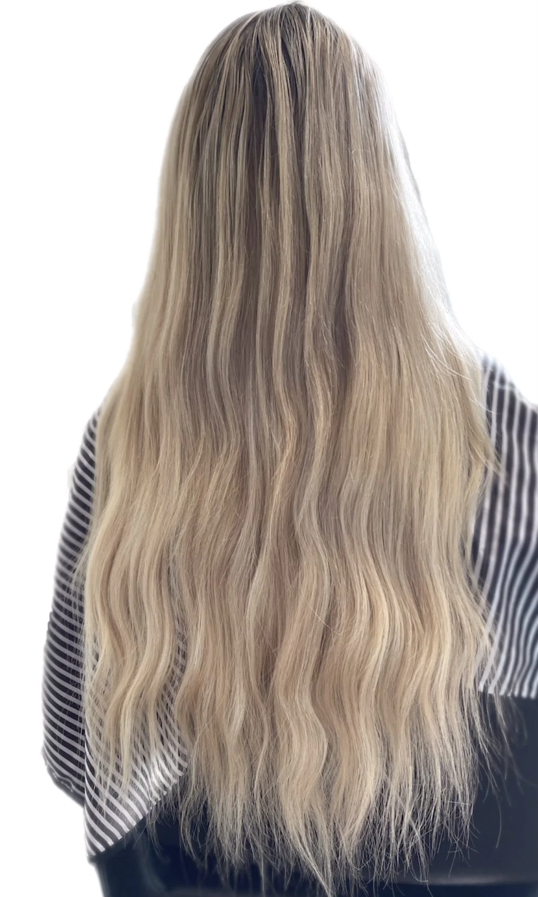 Long, wavy, blonde hair seen from the back, wearing a striped shirt.
