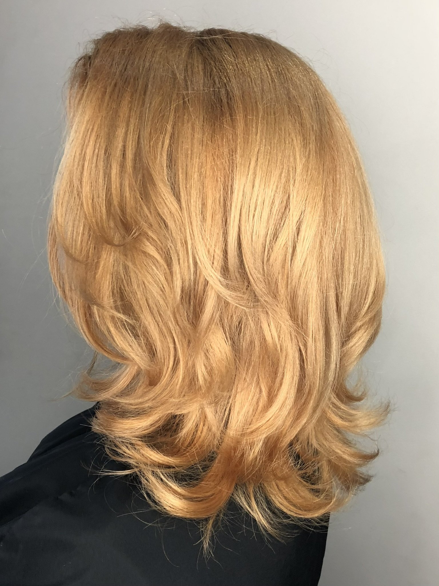 Back view of a person's shoulder-length, wavy, blonde hair.