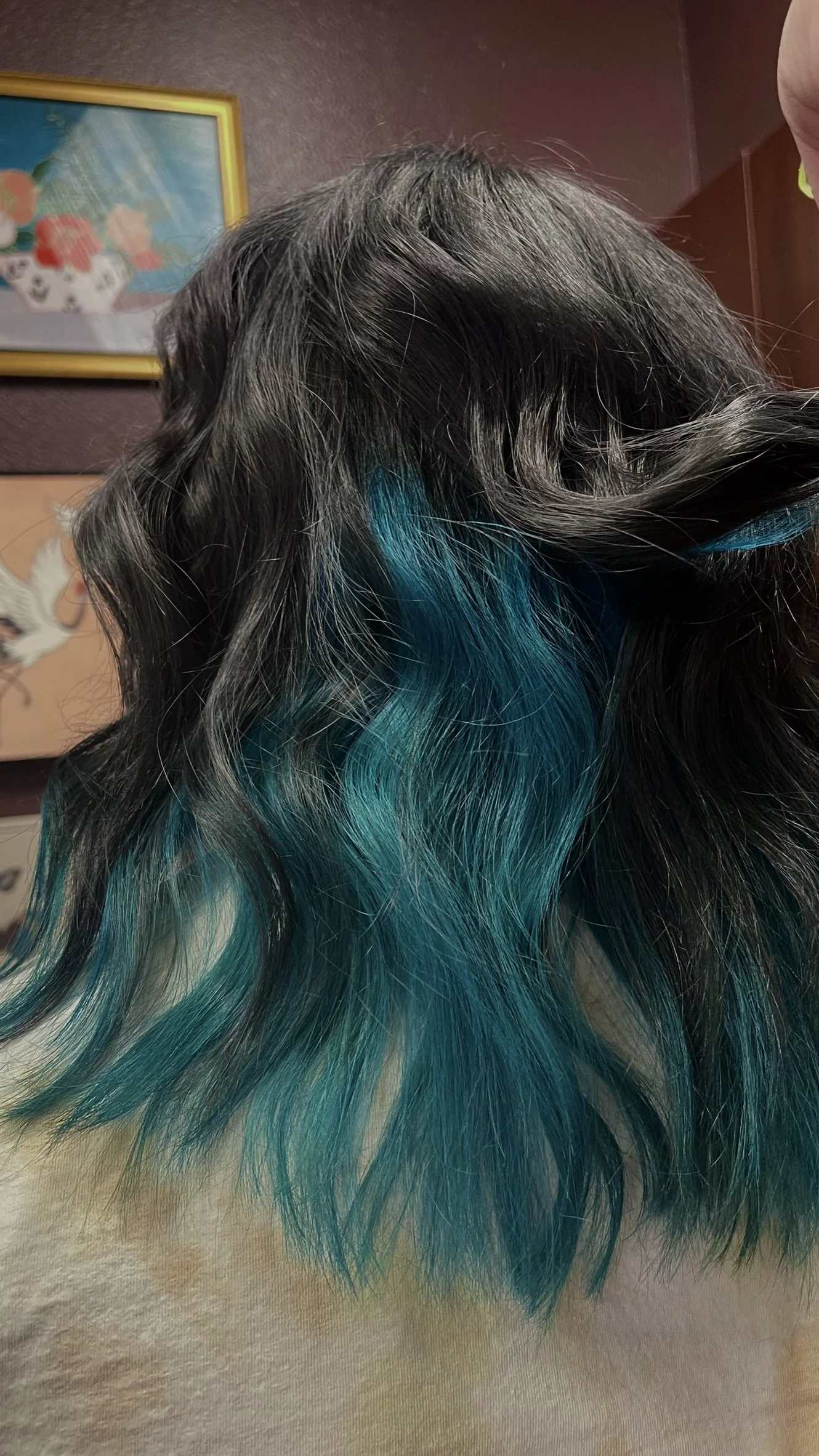 Close-up of black wavy hair with turquoise highlights.