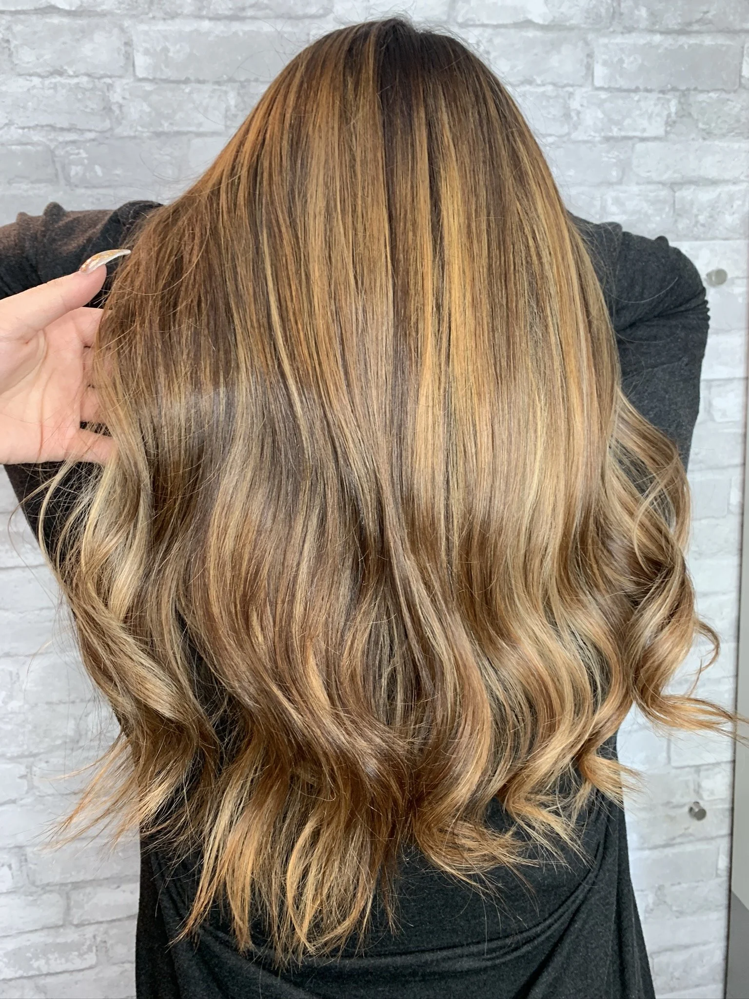 Back view of a woman with long, wavy, caramel-colored hair.