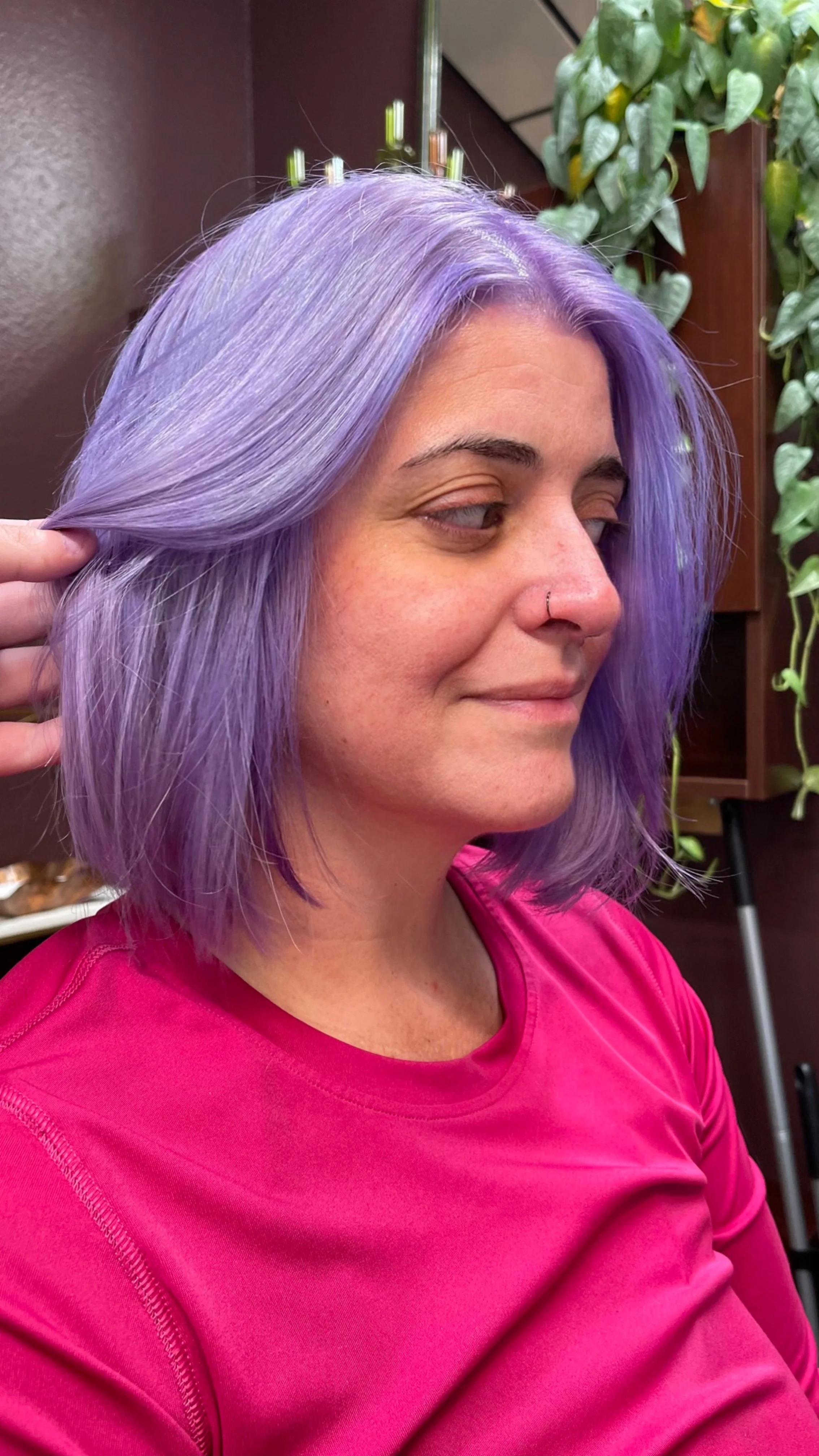 Woman with shoulder-length purple hair getting her hair styled at a salon.