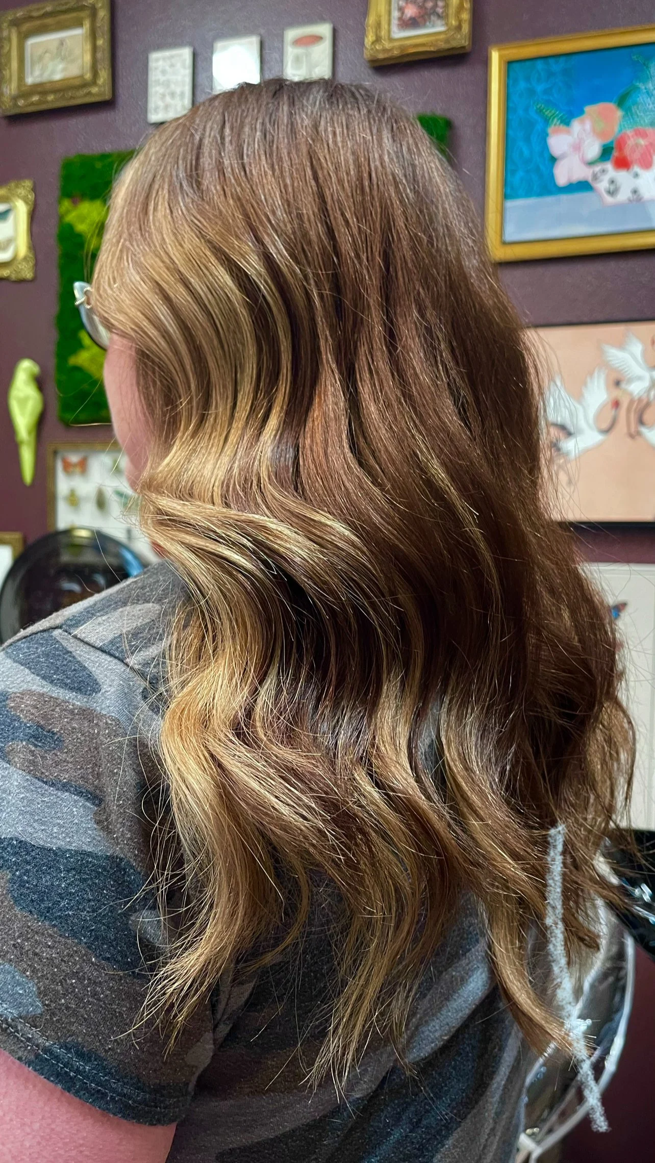 Woman with wavy, brown hair with blonde highlights sitting in a salon.