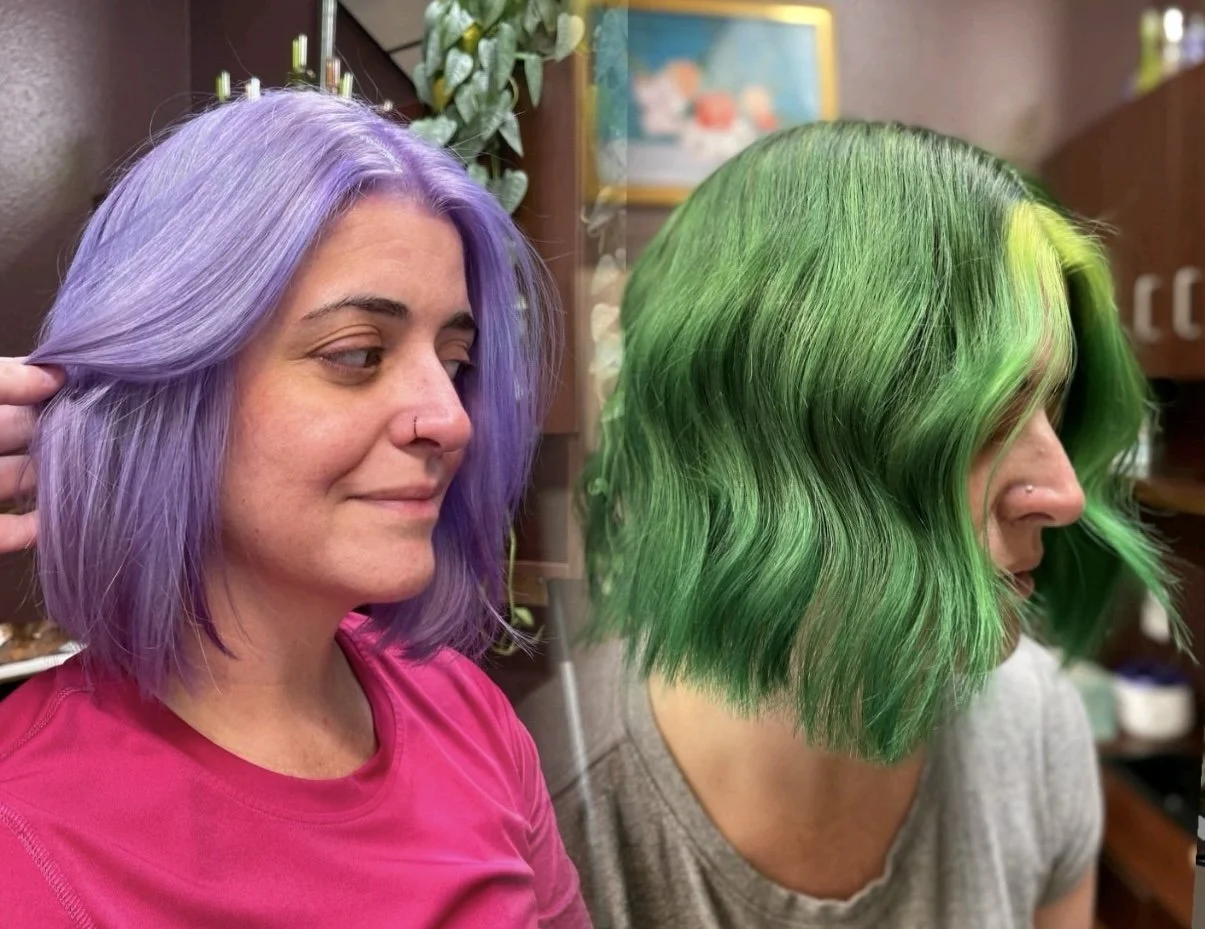 Two women with colorful hair, one with purple hair and the other with green hair, in a hairstylist's salon.