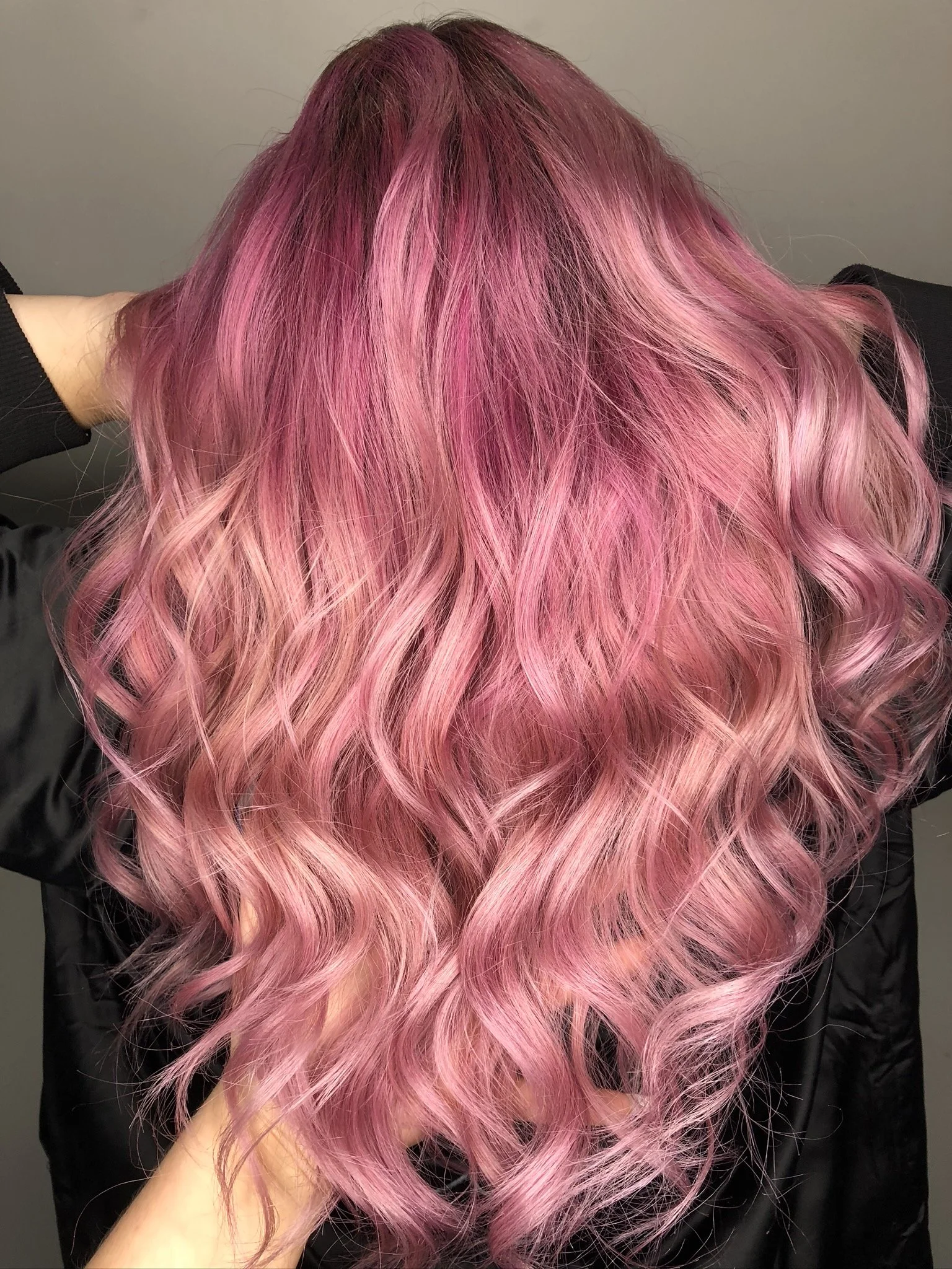 Long, wavy hair dyed in shades of pink, with darker roots and lighter ends.