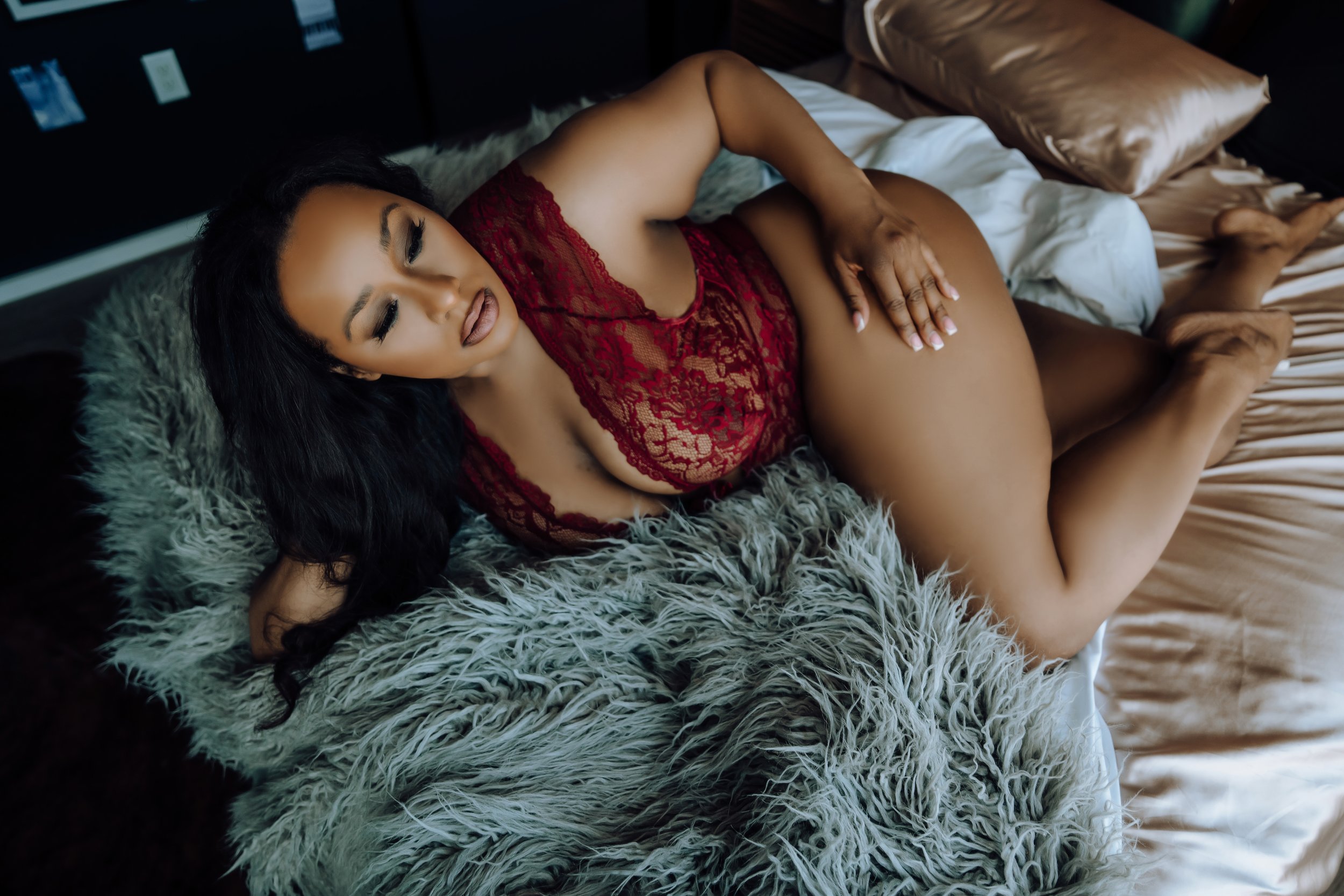 Black woman wearing burgandy lace teddy, woman of color over 40, lying on a bed, plus size boudoir photography, Holly Douglas and Company, Nashville, TN