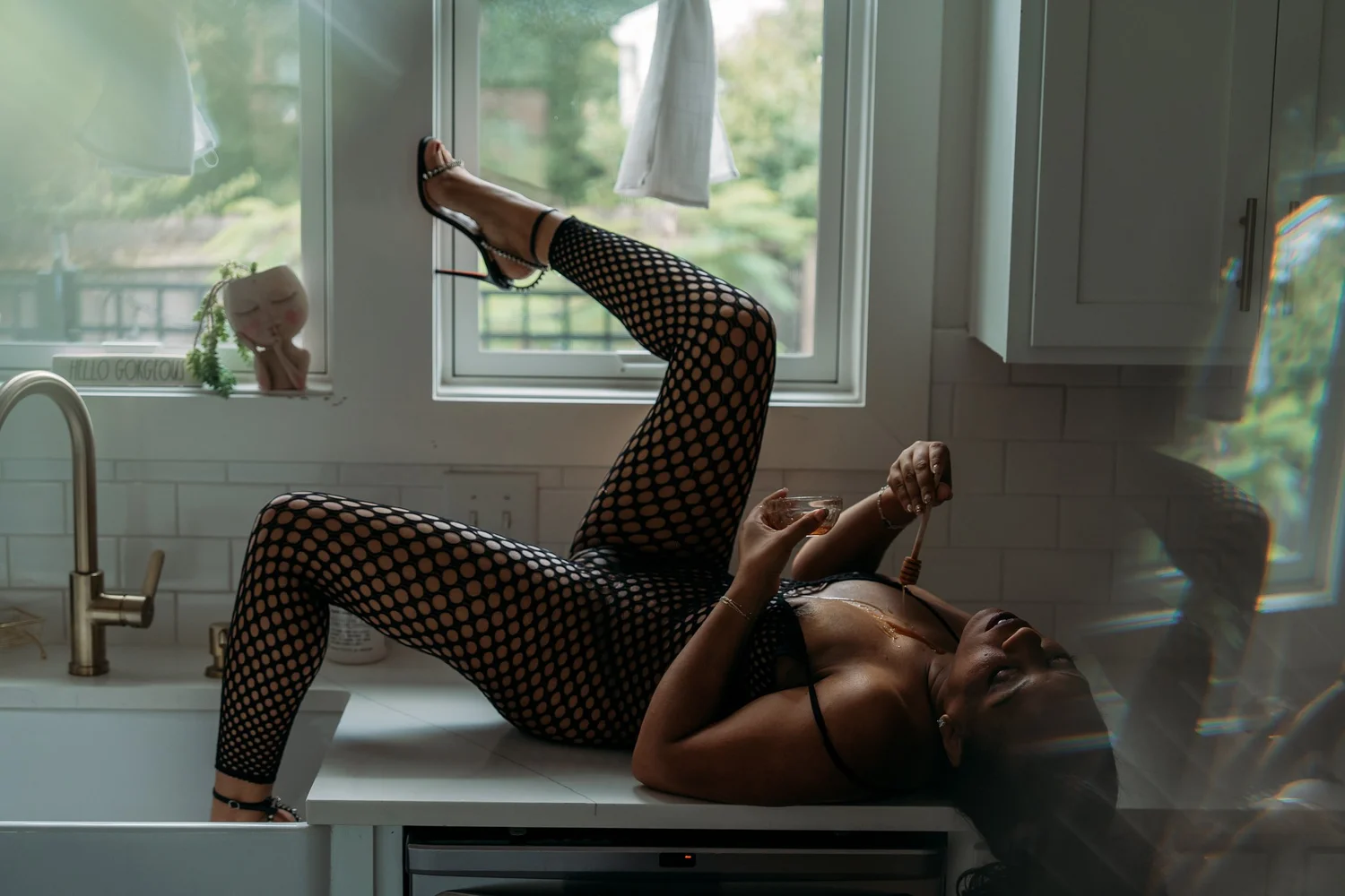 Client posing by the window in a black bodysuit