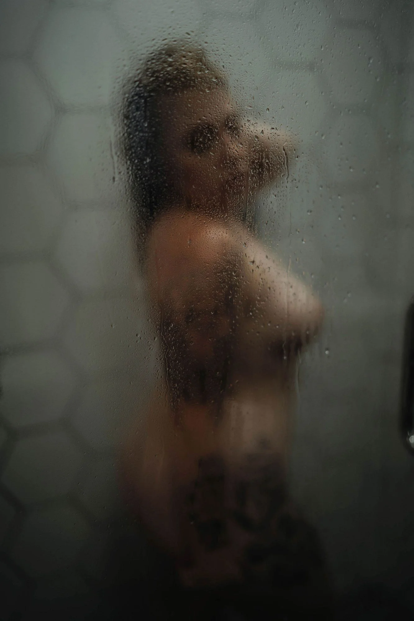 Blurred figure behind steamy glass in a white tile shower, Nashville boudoir add-on sets