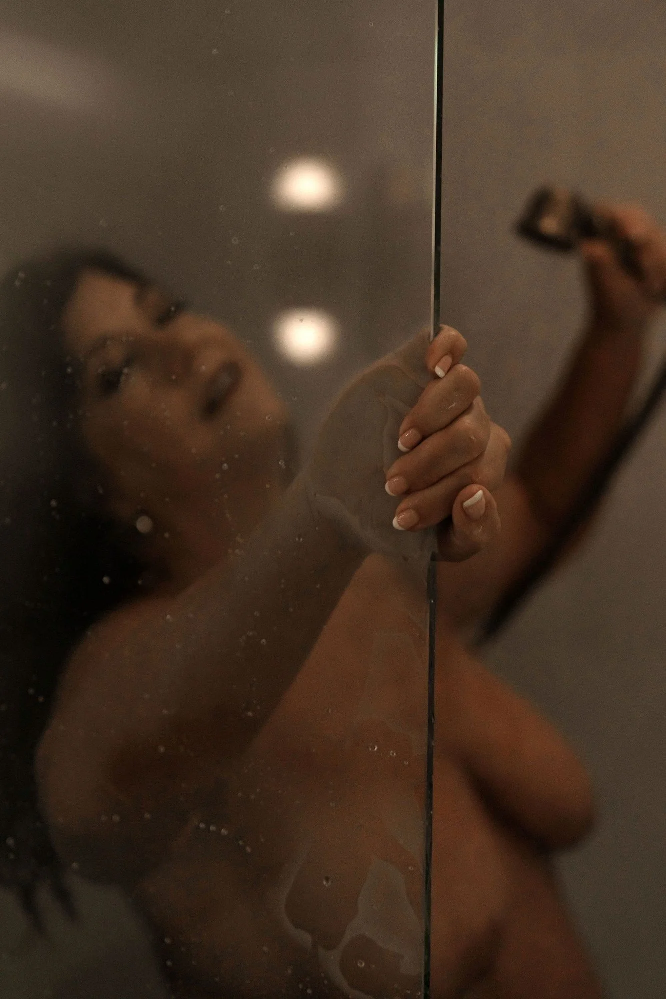 Woman gripping the shower door behind wet glass with warm lights, Shower add-on set in Nashville, TN