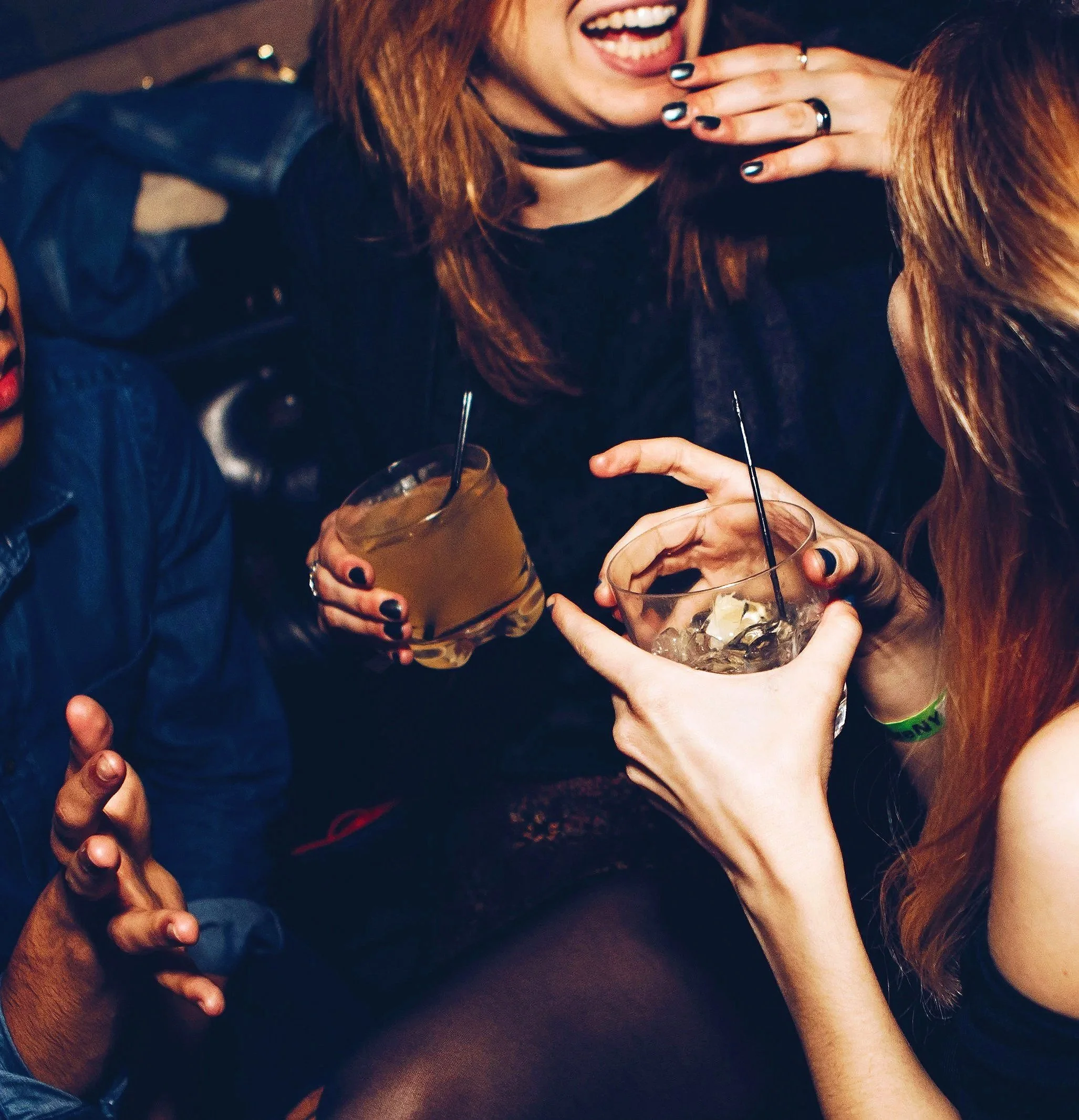 Two women holing drinks at party with one laughing
