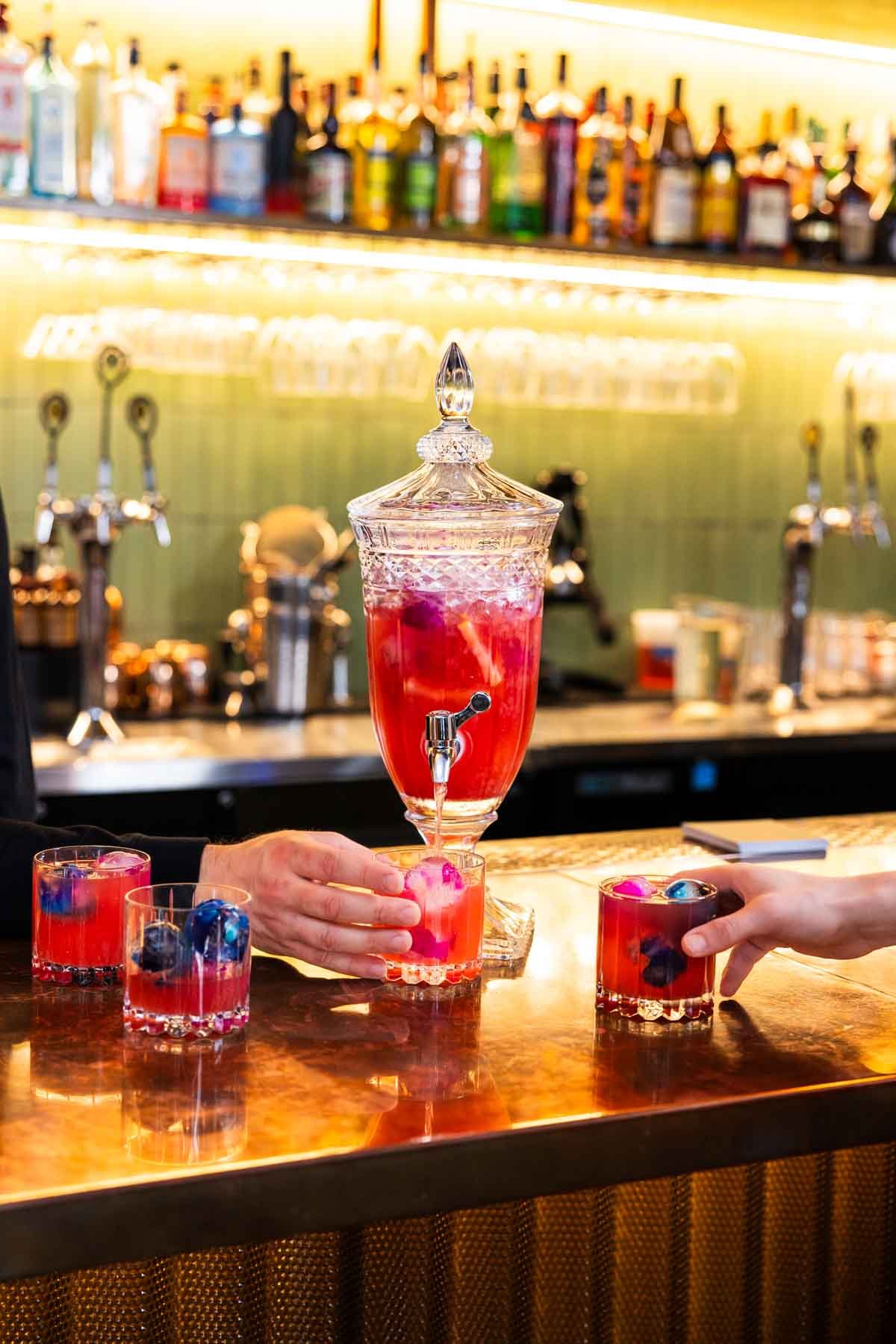 A red cocktail punch served from a crystal dispenser on the bar at Protocol in Amherst, MA