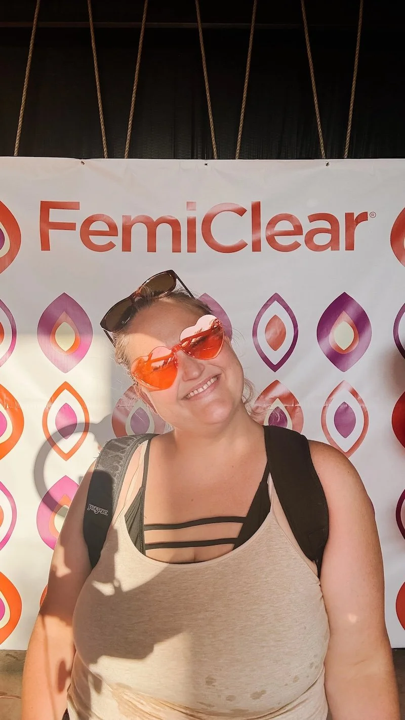 Woman at YouMeShe festival standing in front of FemiClear sign