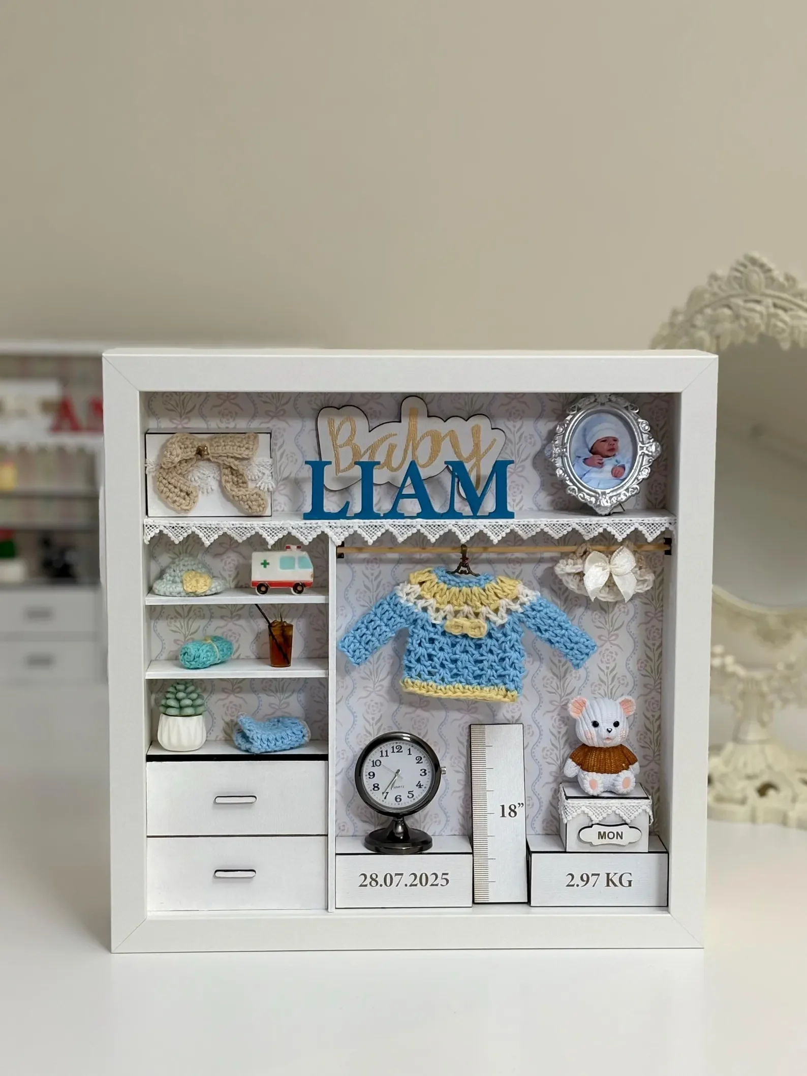 a white wooden shadow box for a new baby.