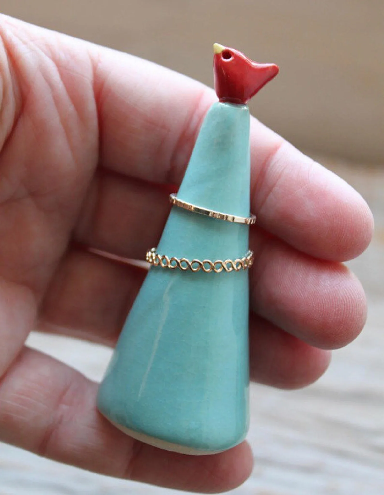A Lovely little air dry clay ring cone in a variety of colors with a tiny bird perched on top.