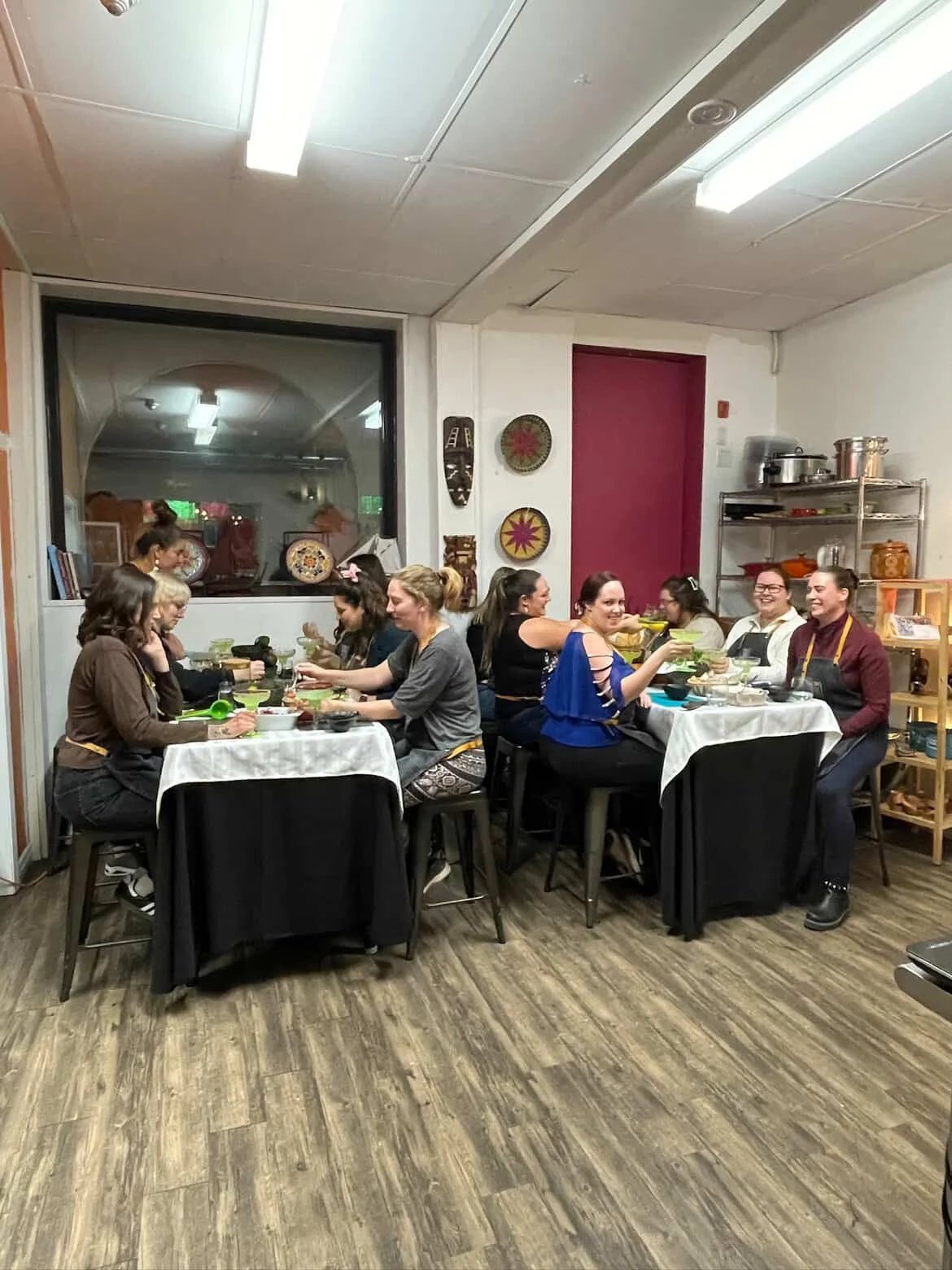Group of moms taking part in a hands-on cooking class at La Hacienda in Peterborough, smiling and preparing food together during a Moms’ Night Out event hosted by First Five Club..