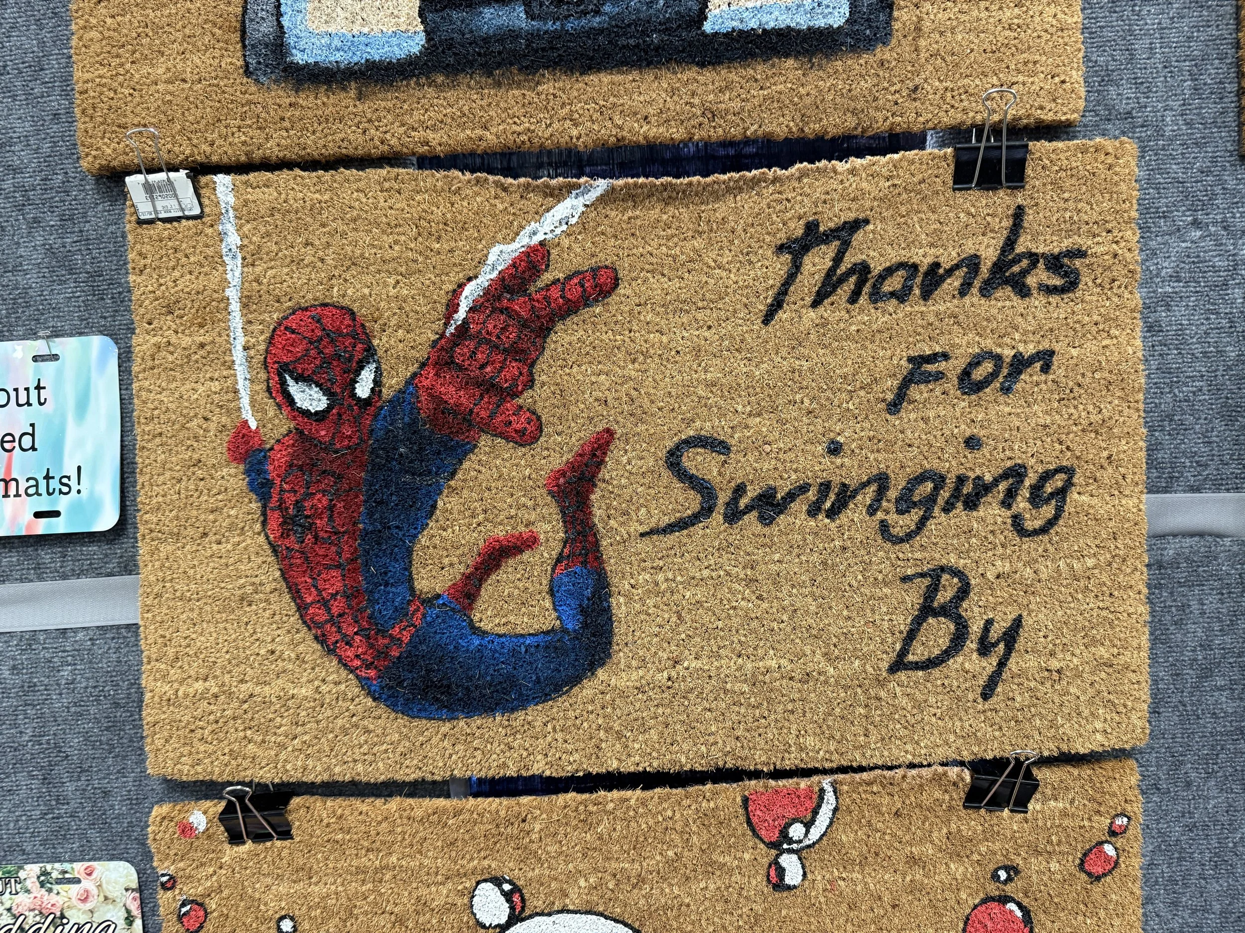 A doormat with a cartoon image of Spider-Man pointing at a sign that reads, "Thanks for Swinging By."