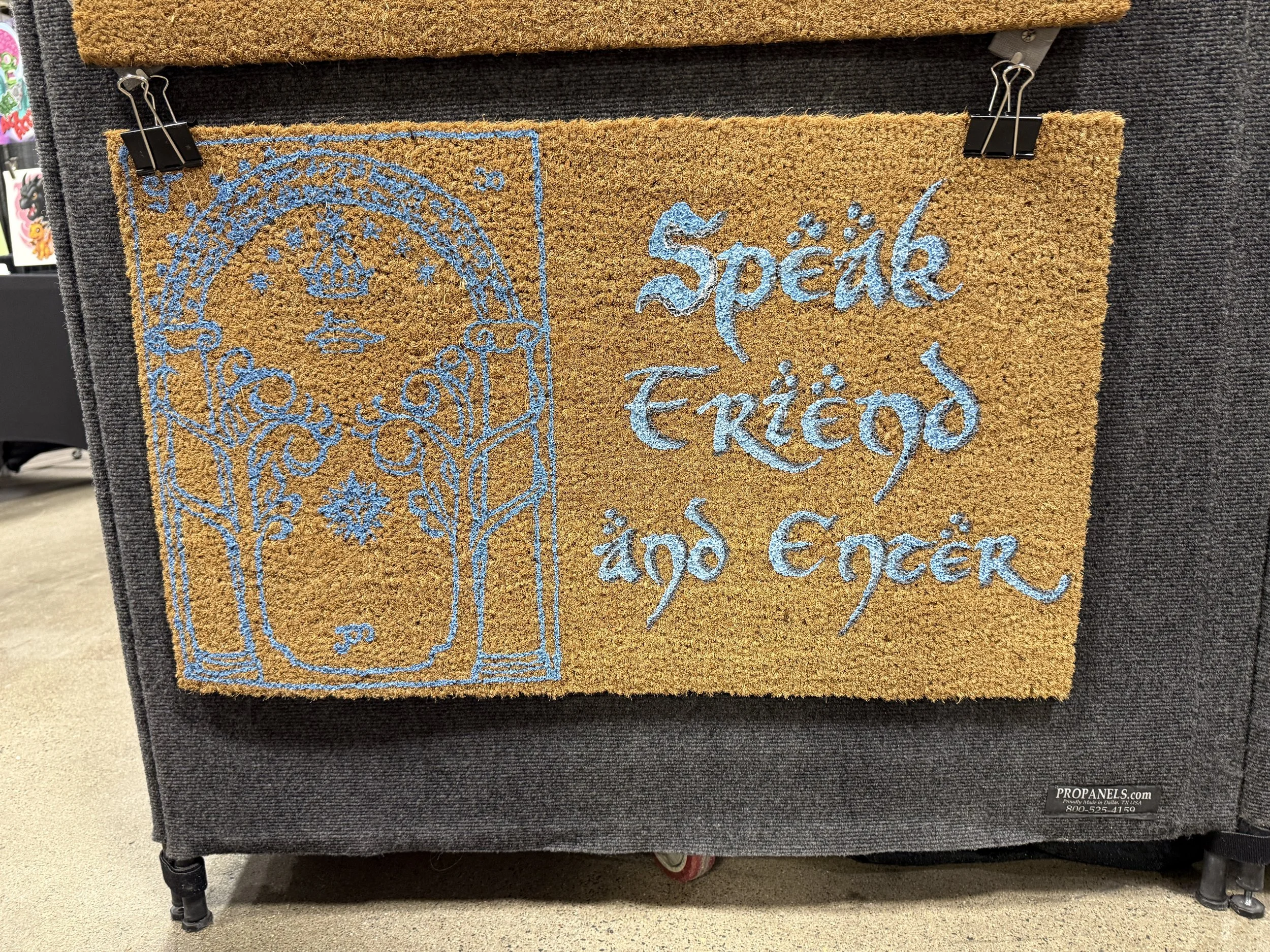 Decorative doormat with a tree design and the text 'Speak Elvish and Elcor' in blue embroidery.