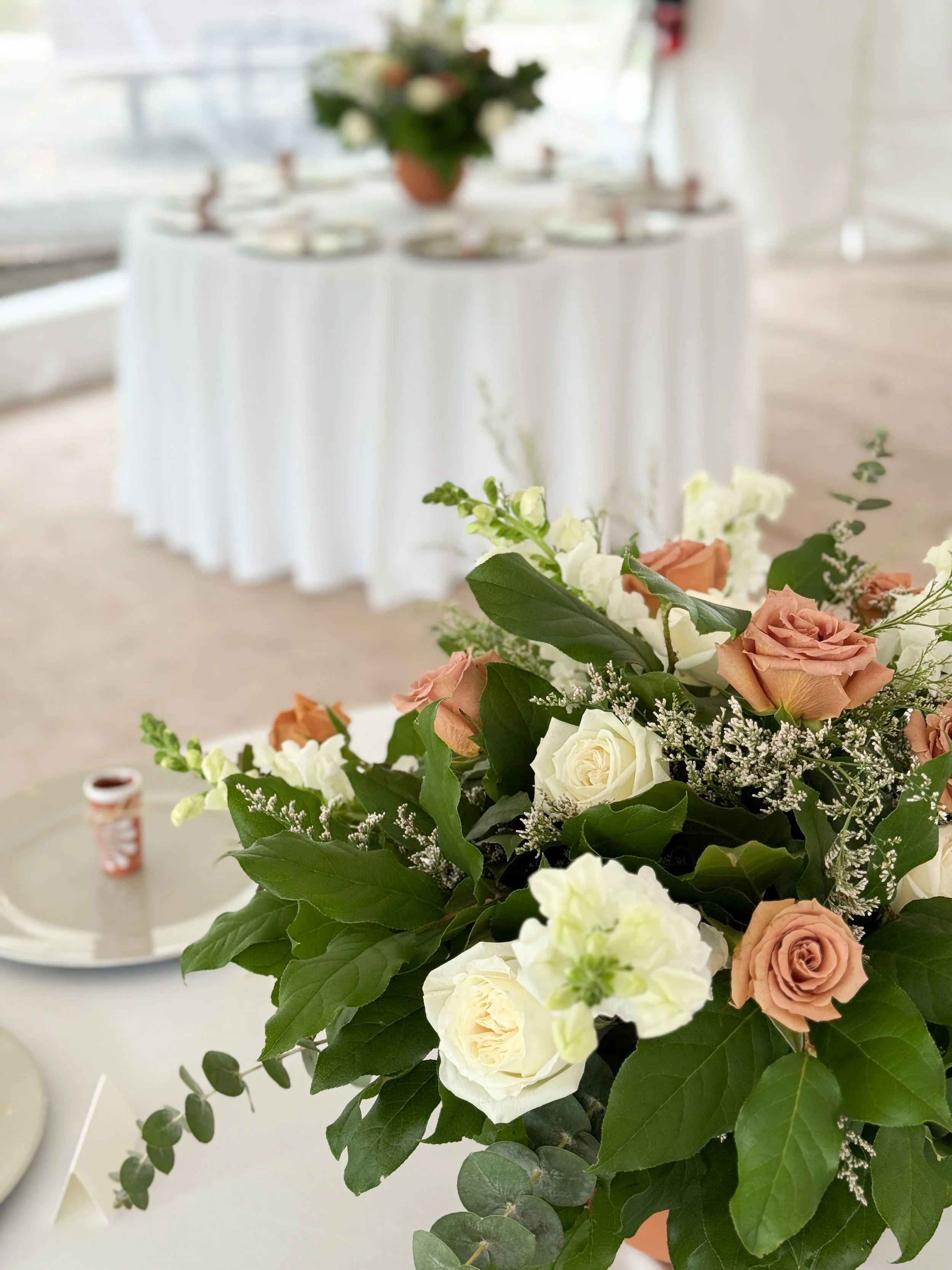 Wedding centerpiece with terracotta vase with white playa blanca roses and toffee roses