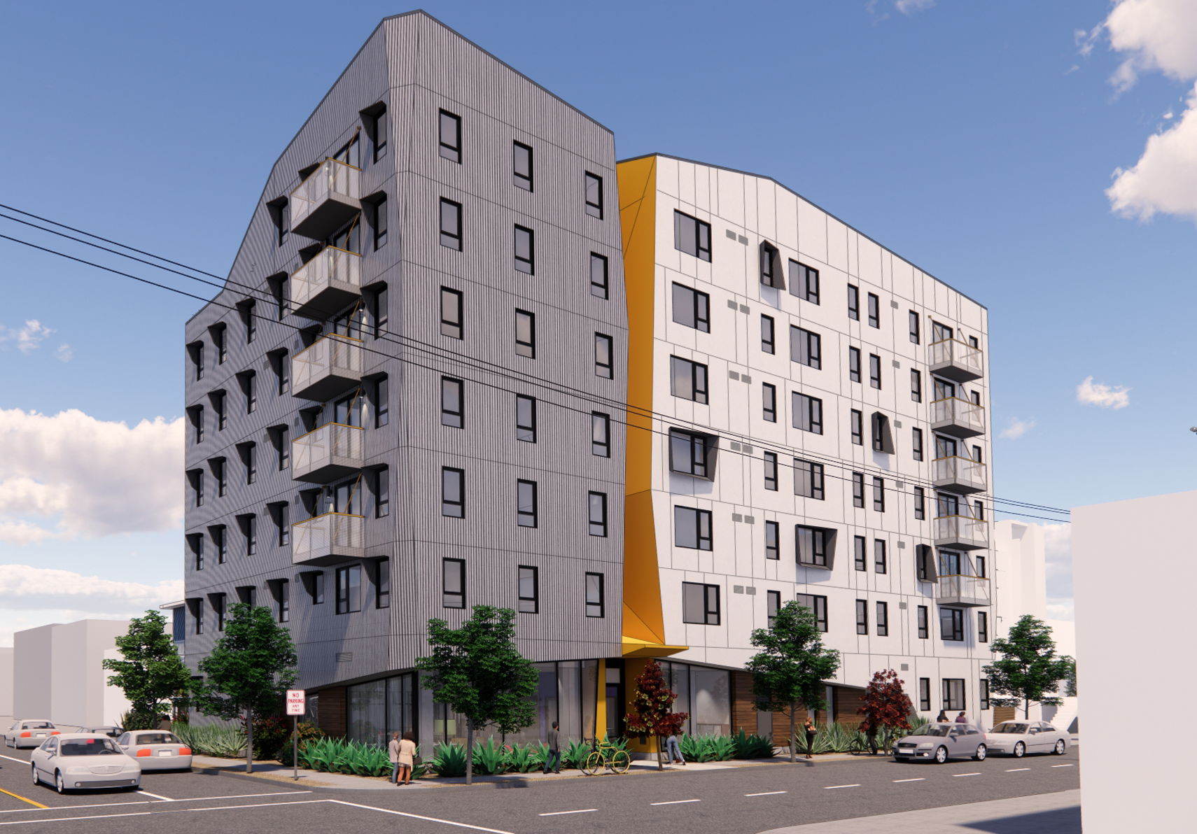 Modern multi-story apartment building with a distinctive curved facade, gray and white exterior panels, and yellow accent. The building has balconies, large windows, and ground-floor retail space, with trees and parked cars along the street.