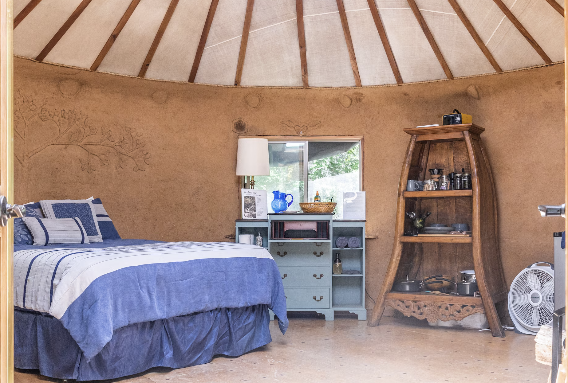 The Earthen Yurt ~ Drift into dreams beneath the captivating Tree of Life headboard, surrounded by lunar cycles adorning the interior walls.