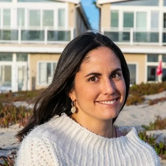 Person practicing yoga tree pose on train tracks, wearing black leggings and a red sports bra, surrounded by trees.