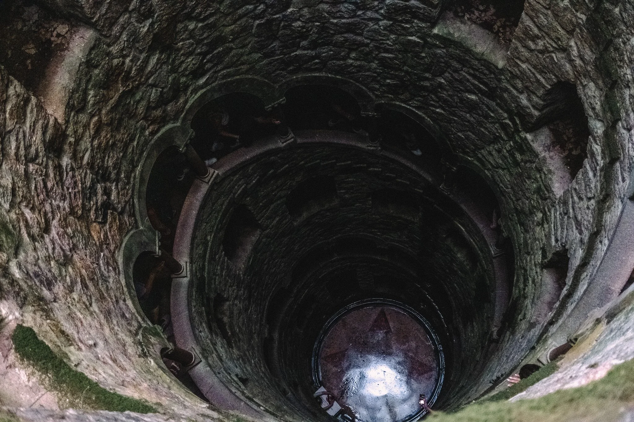 An ancient stone well with a spiral staircase around its interior wall leading downward.