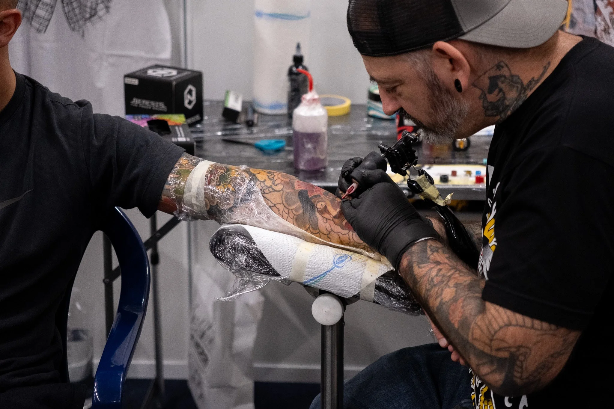Tattoo artist creating a colorful tattoo on a client's arm in a tattoo studio.