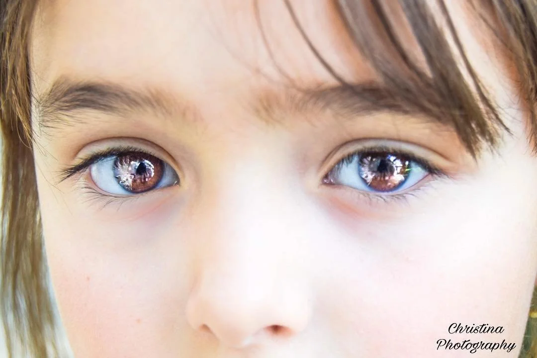 Close-up of a child's face with focus on blue eyes reflected in the corneas.