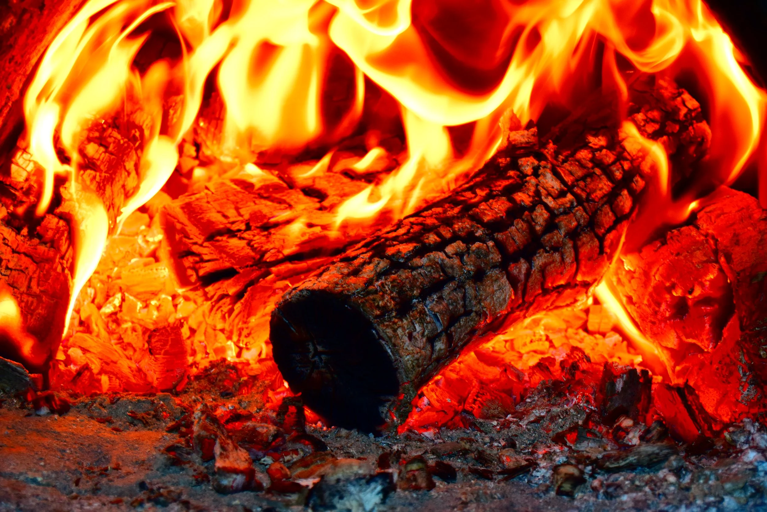 A burning log in a fire with bright orange flames.