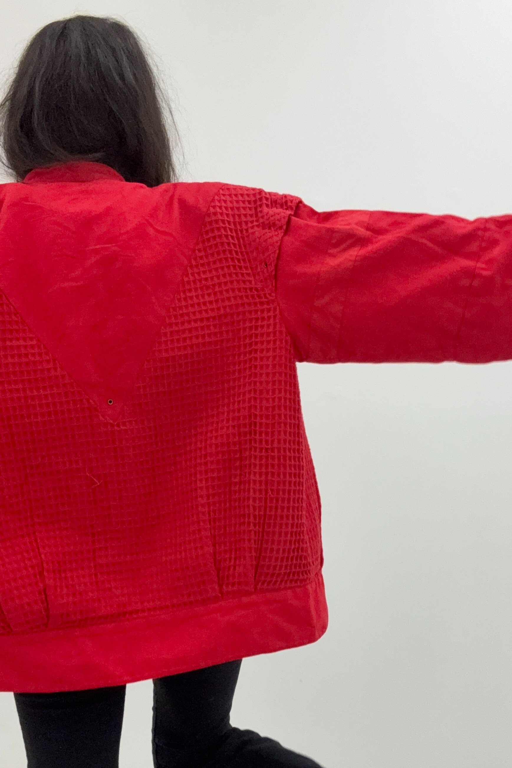 A full back shot of a vintage 80s Claude Montana red jacket, showcasing its unique, intricate design elements.