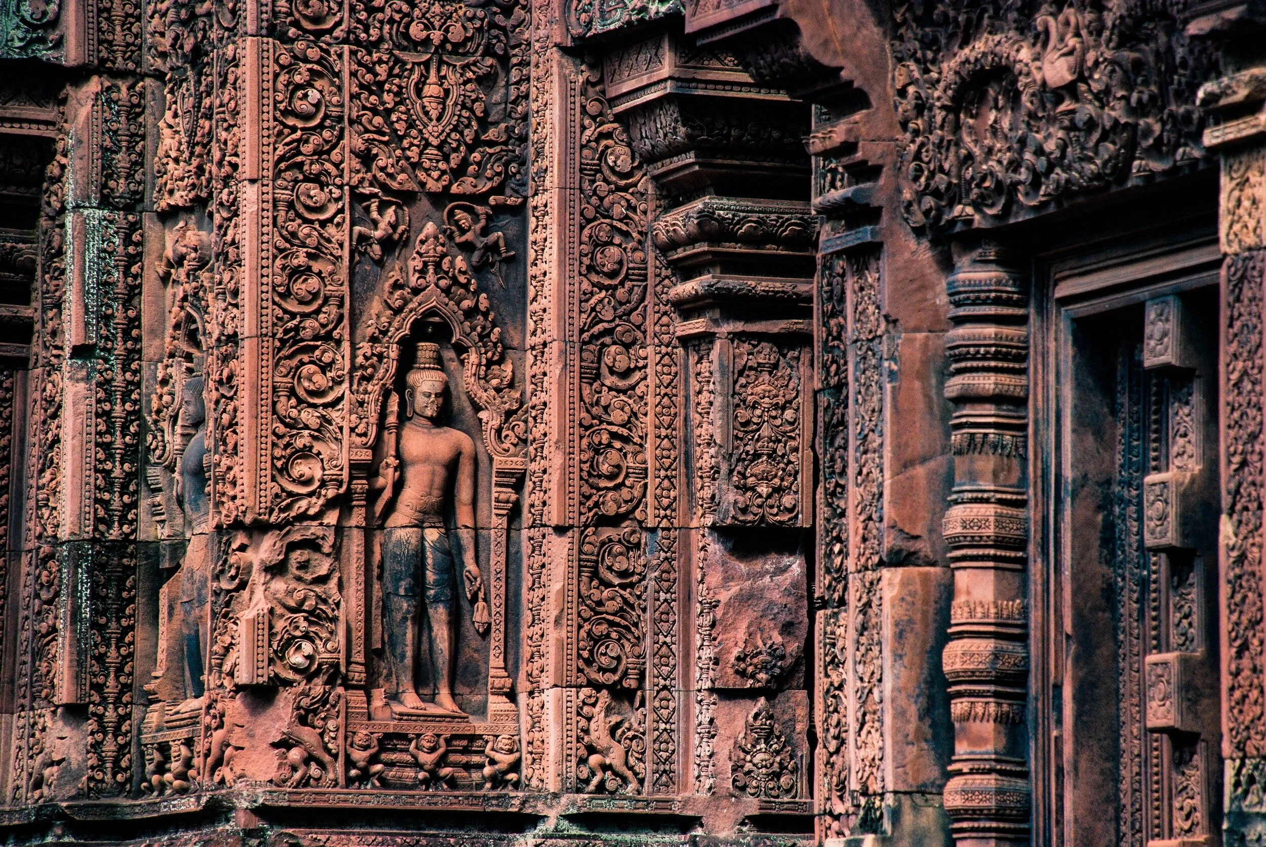 Close-up view of intricate stone carvings and sculptures on an ancient temple wall.
