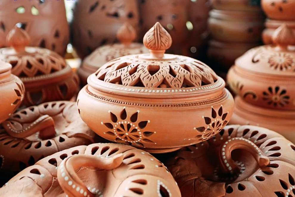 A collection of terracotta incense holders with intricate cutout designs, some with lids, displayed closely together.