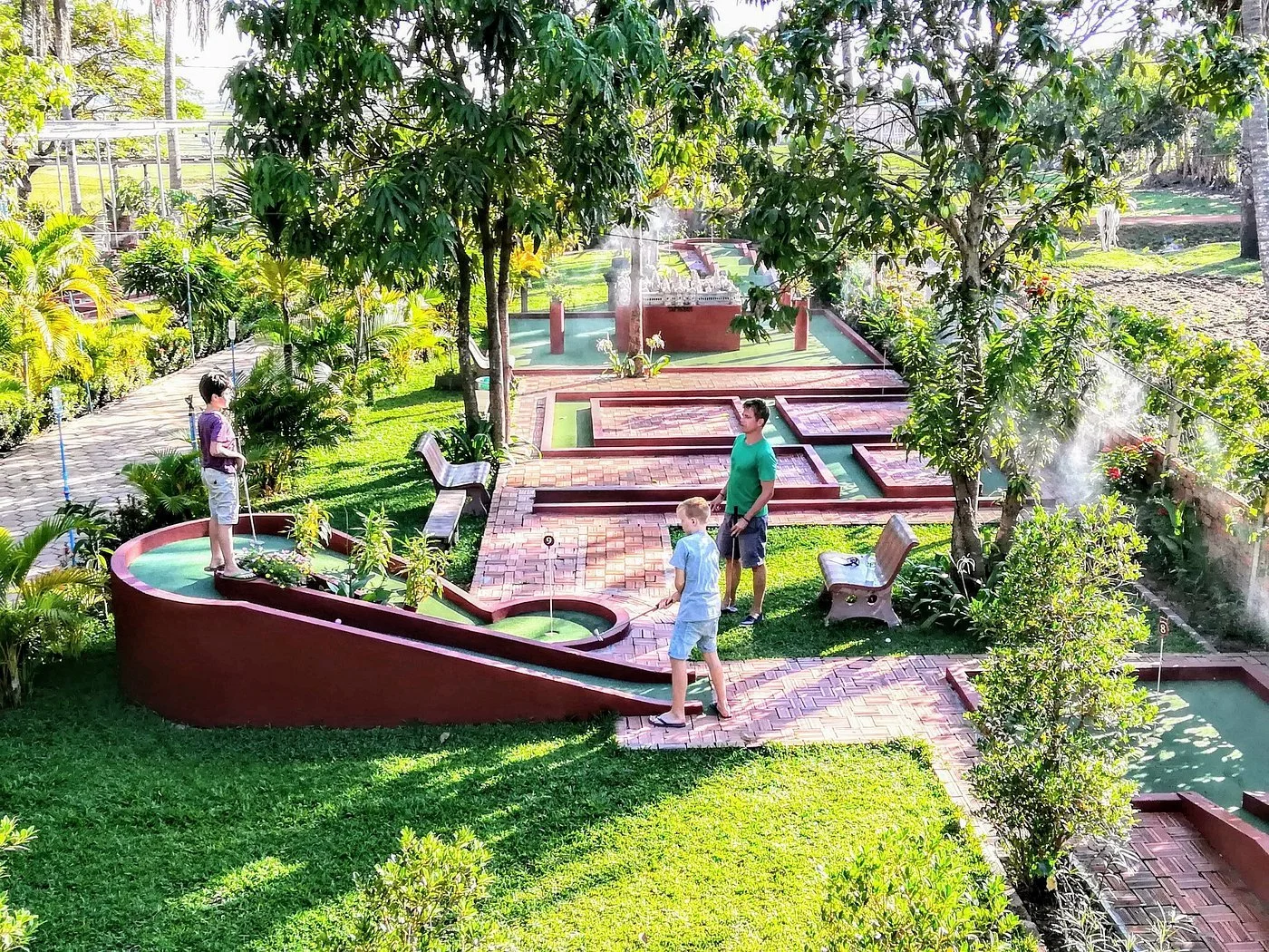 Family playing at Angkor Wat Putt mini-golf course in Siem Reap, featuring miniature Cambodian temple obstacles and rice field views.